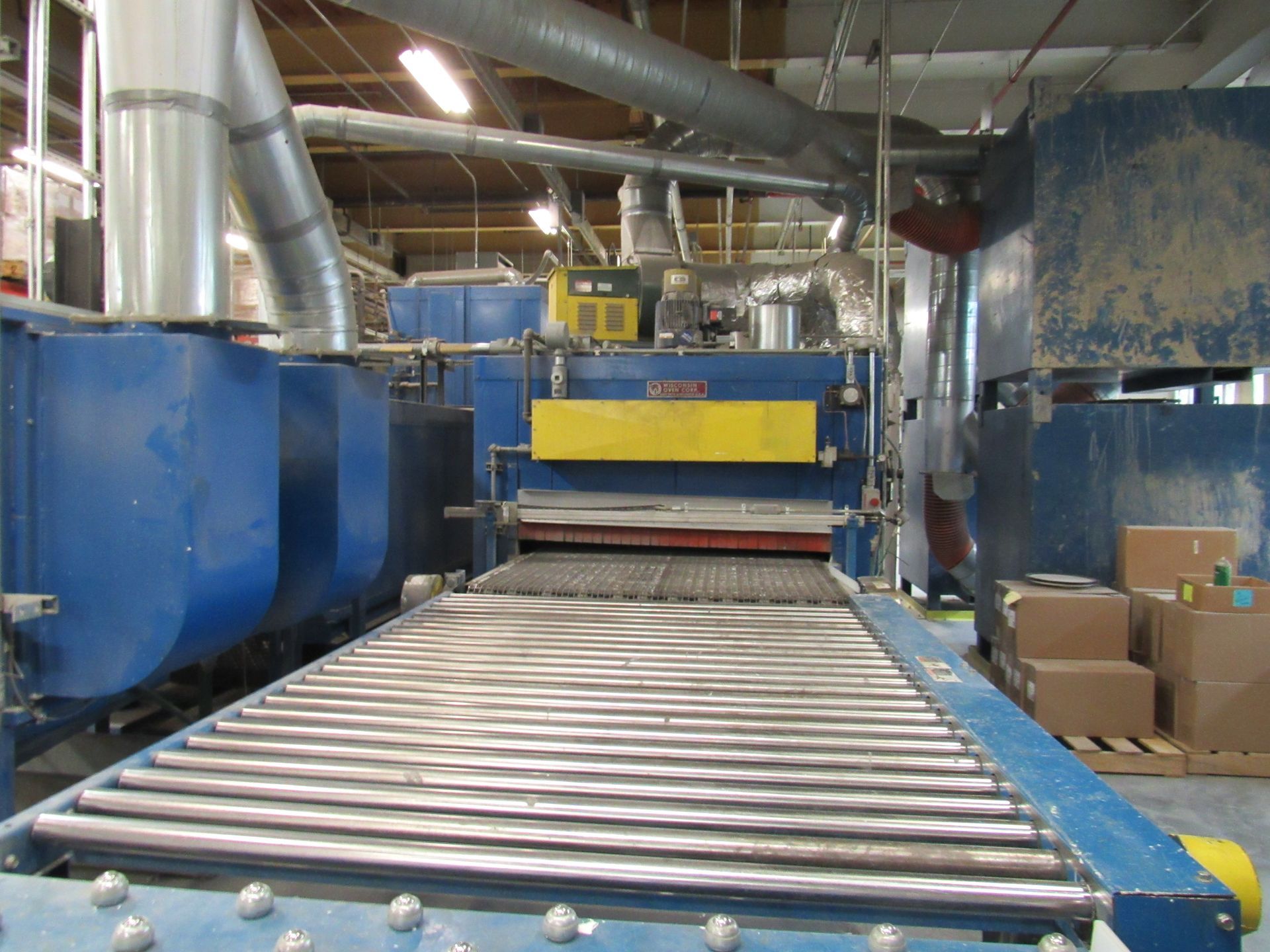 Blue industrial machine with conveyor belt, air ducts, and cardboard boxes.