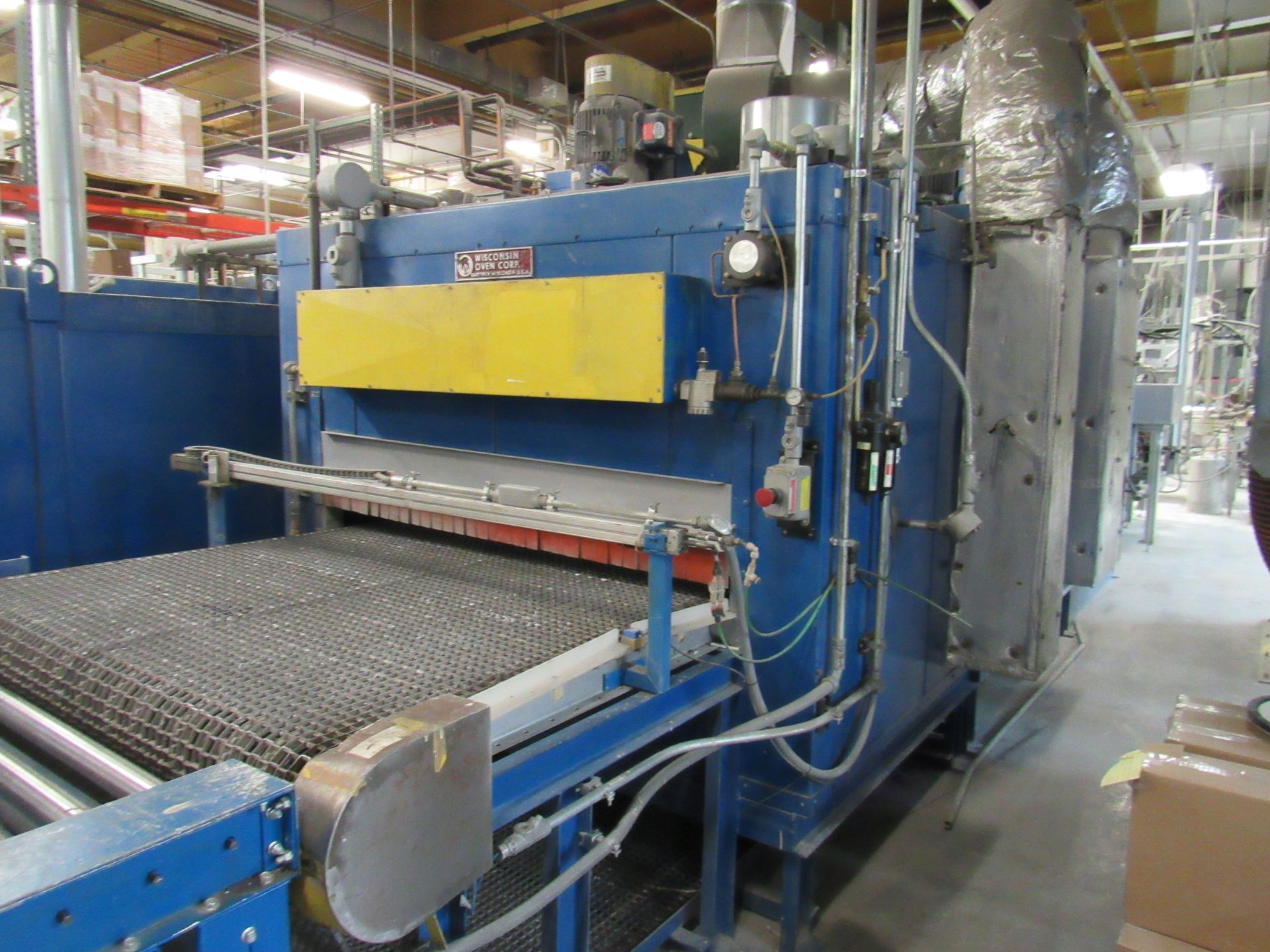 Blue industrial oven with a wire mesh conveyor belt, used for manufacturing.