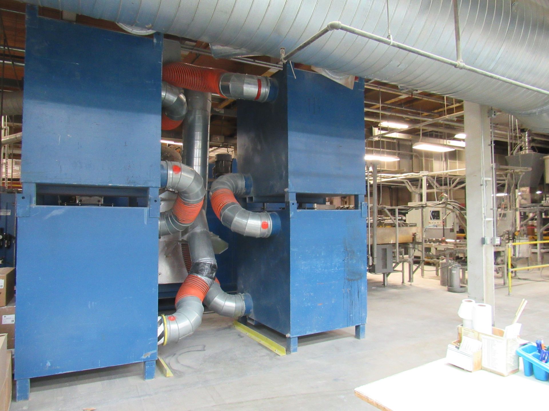 Blue industrial equipment with connected ductwork in a factory setting.