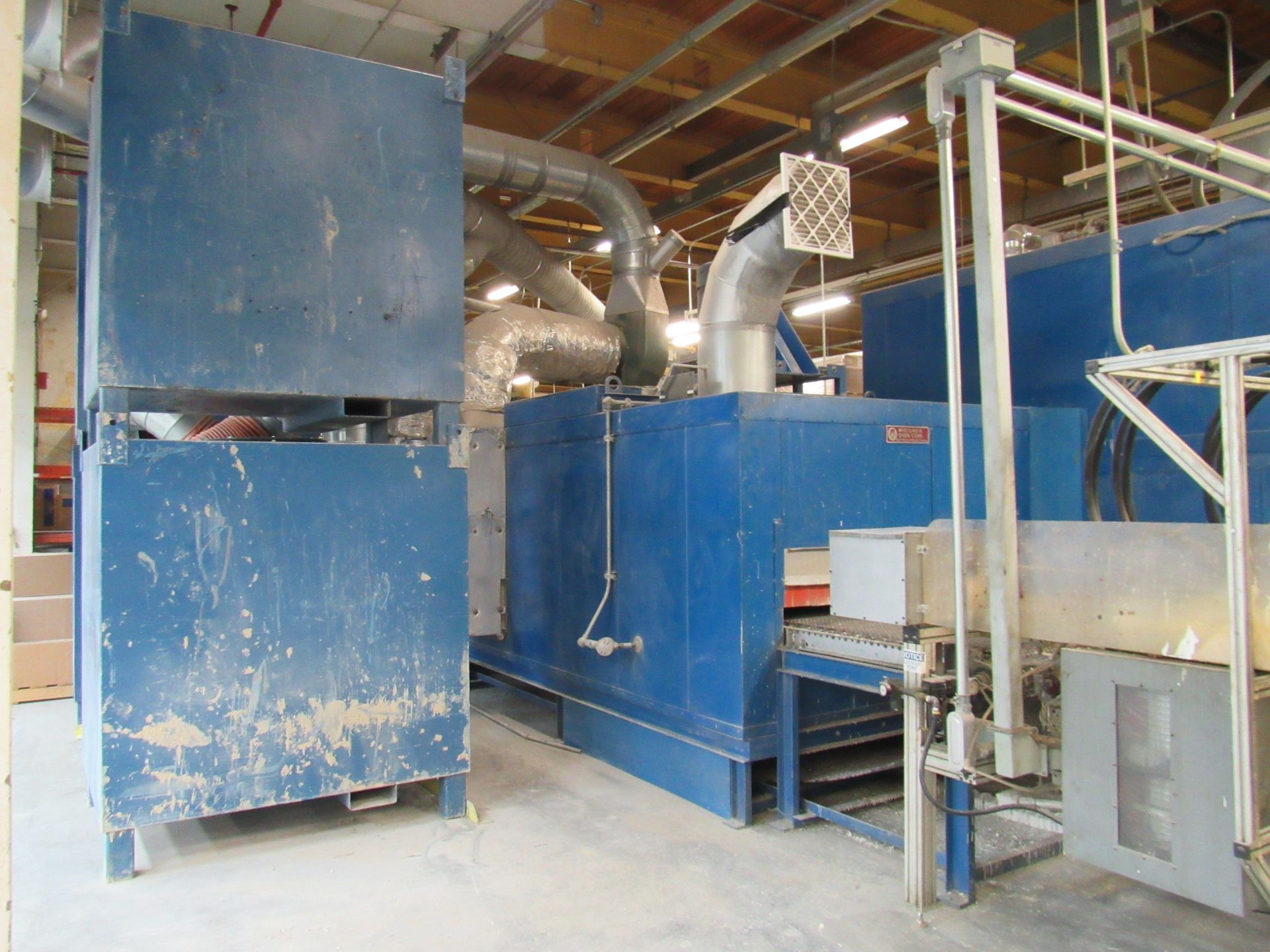 Blue industrial oven with large exhaust pipes in a factory setting.