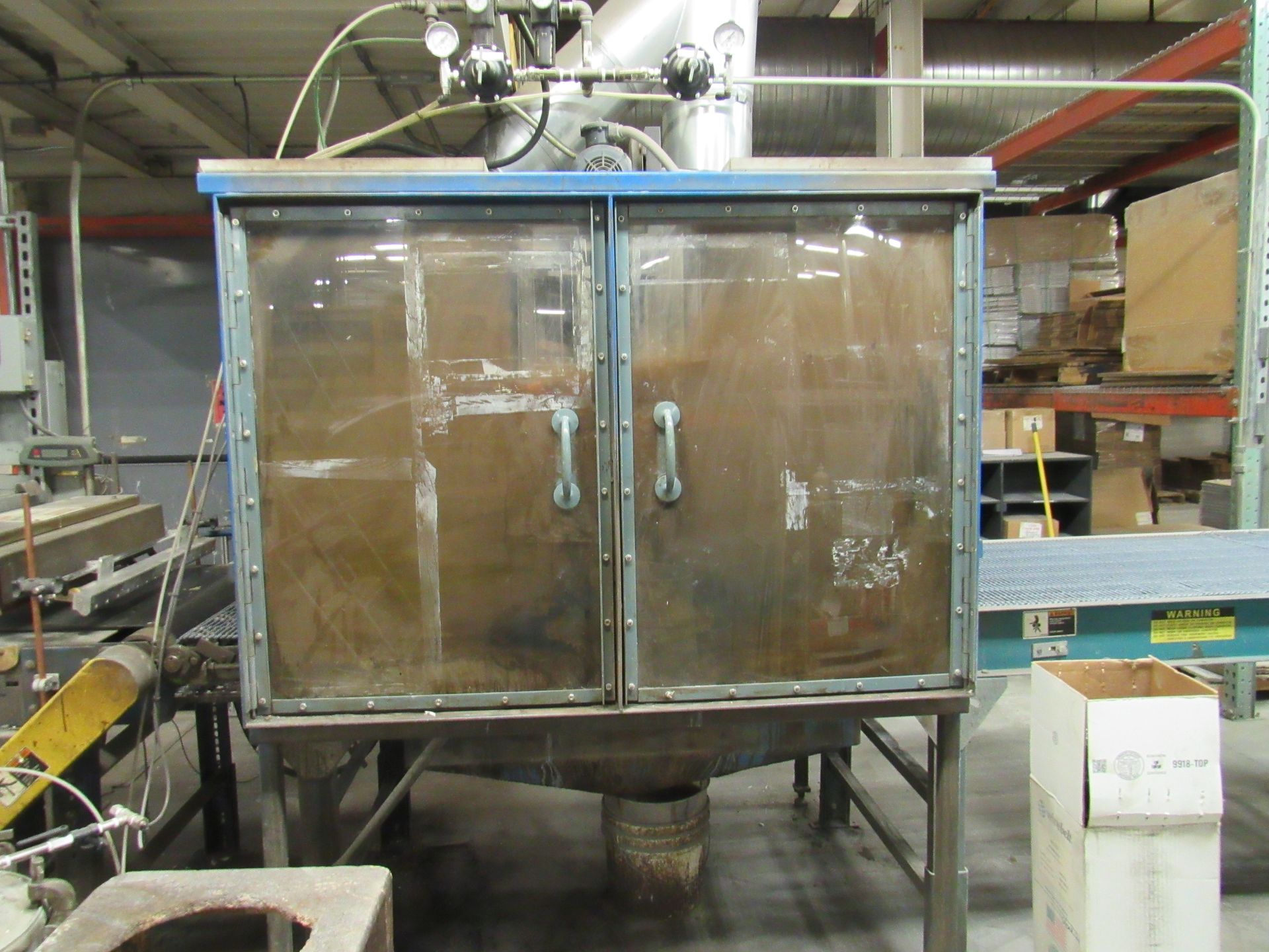 Metal cabinet with clear doors, likely industrial, in a factory setting.