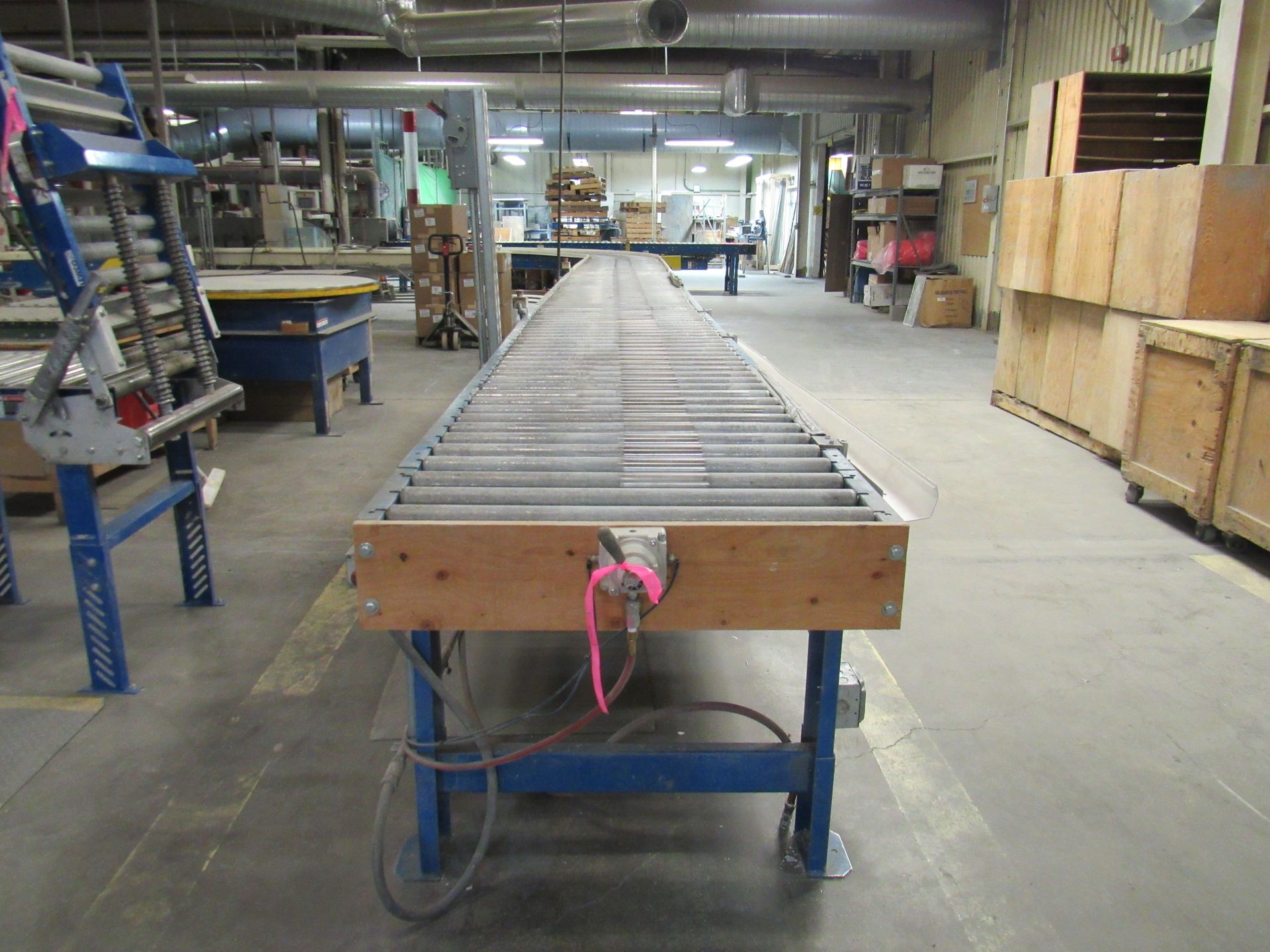 Long industrial roller conveyor on blue wheeled frame in a factory.