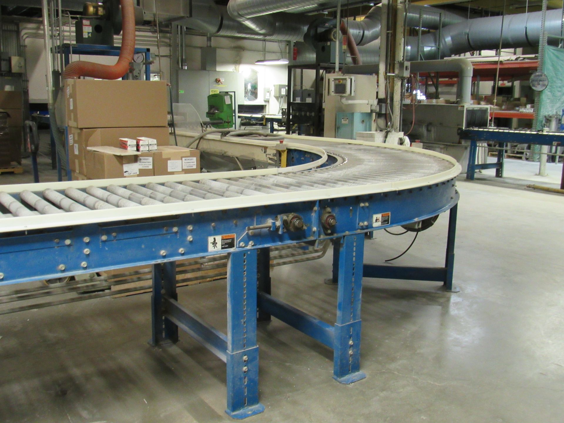 Blue and white conveyor belt in a factory setting, with boxes in the background.