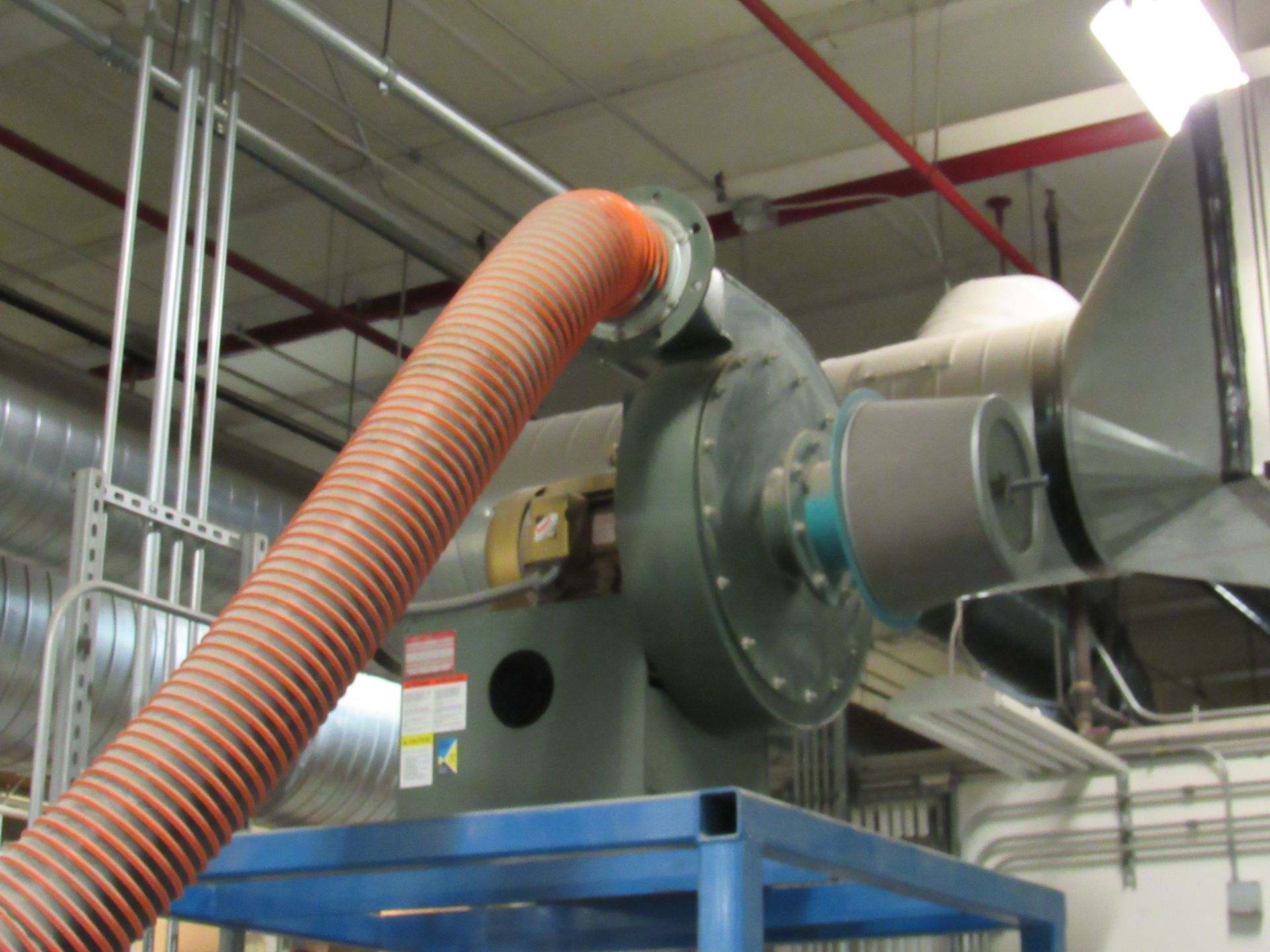 Large industrial fan with orange flexible ducting, mounted on a blue metal stand.