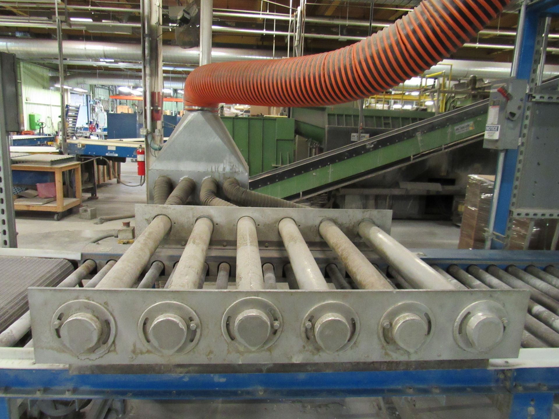 Conveyor belt system in a factory. Orange hose over metal rollers. Industrial setting.