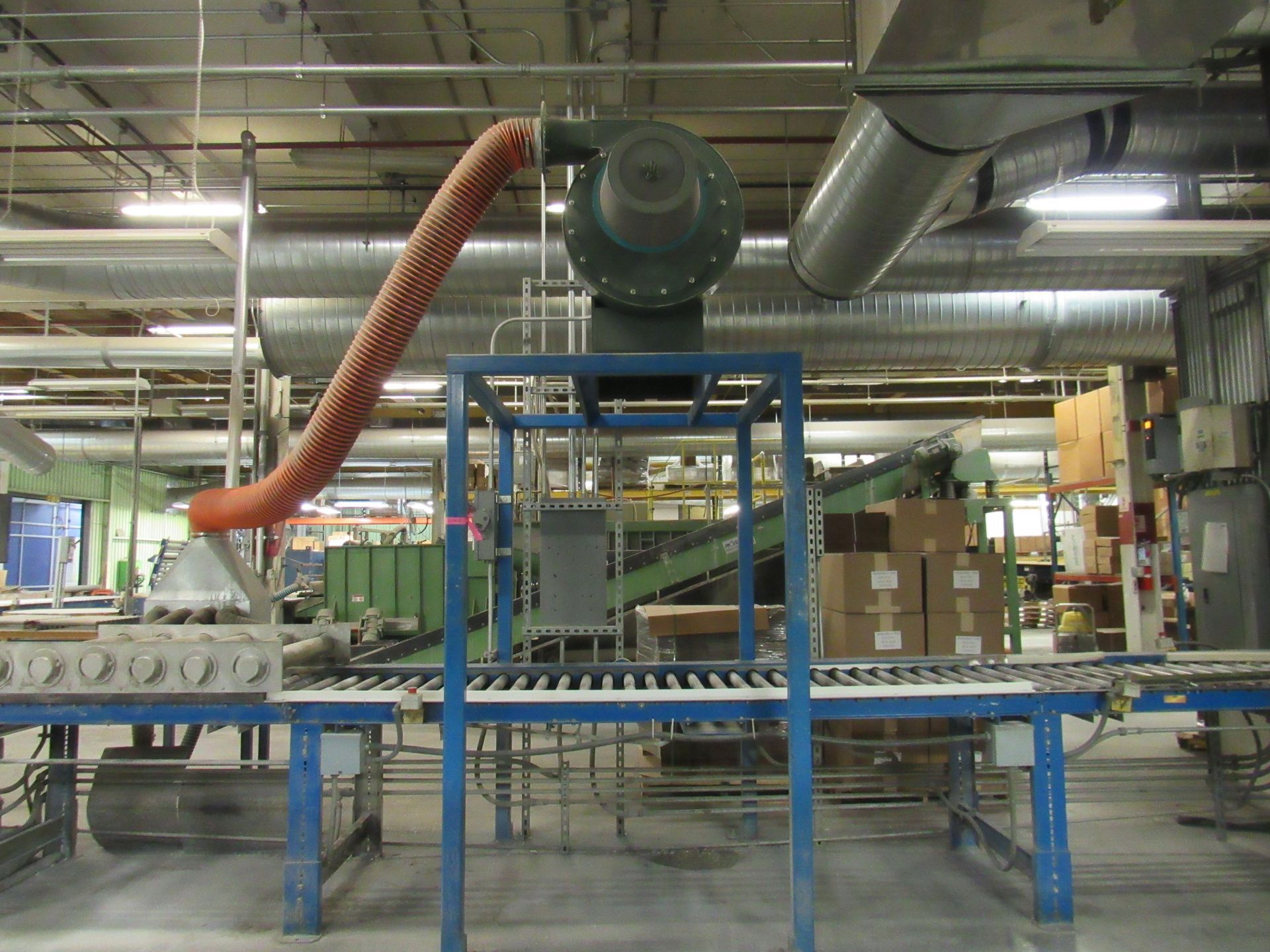 Industrial setting with conveyor belt, fan, and orange flexible duct.