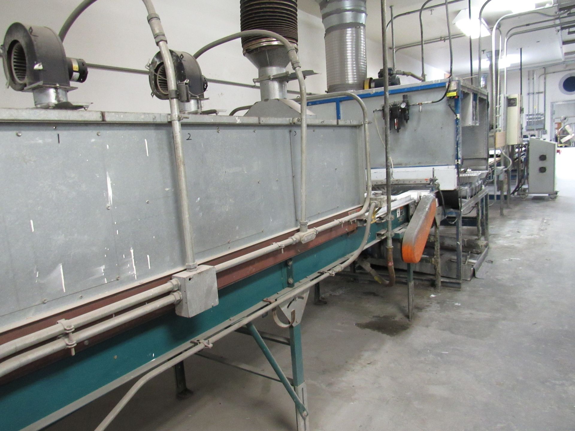 An industrial processing machine with a conveyor belt, pipes, and metal components in a factory.
