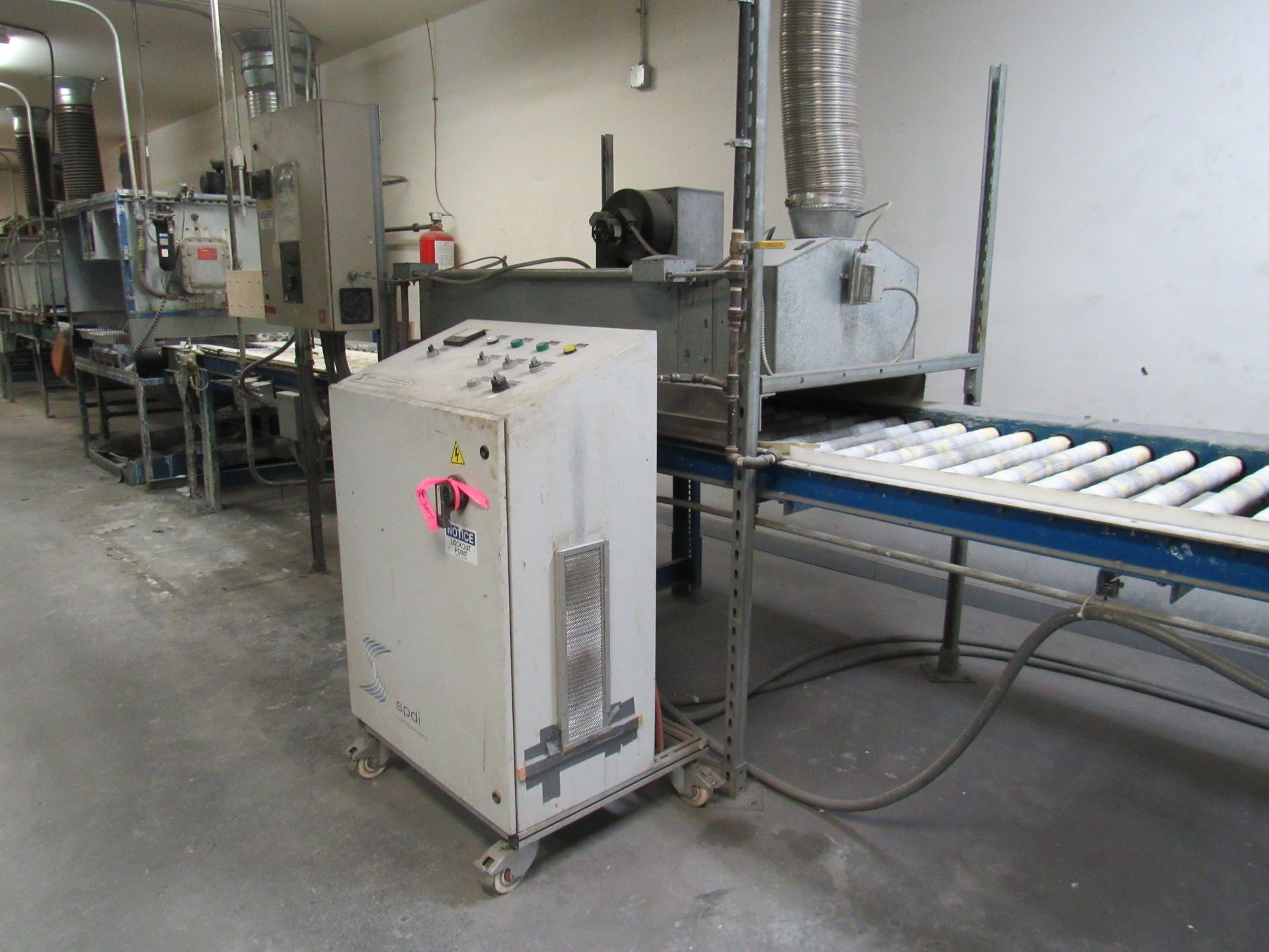 Industrial machinery with a control panel, conveyor belt, and exhaust duct.