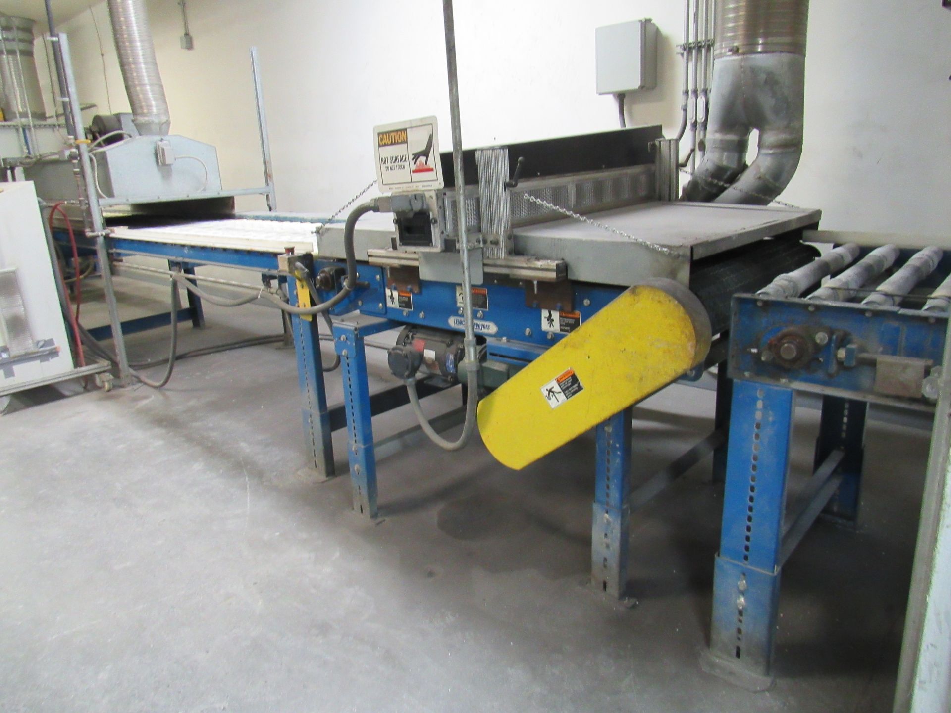 Industrial machine with a conveyor belt and a large cutting blade. Blue supports, yellow safety cover.