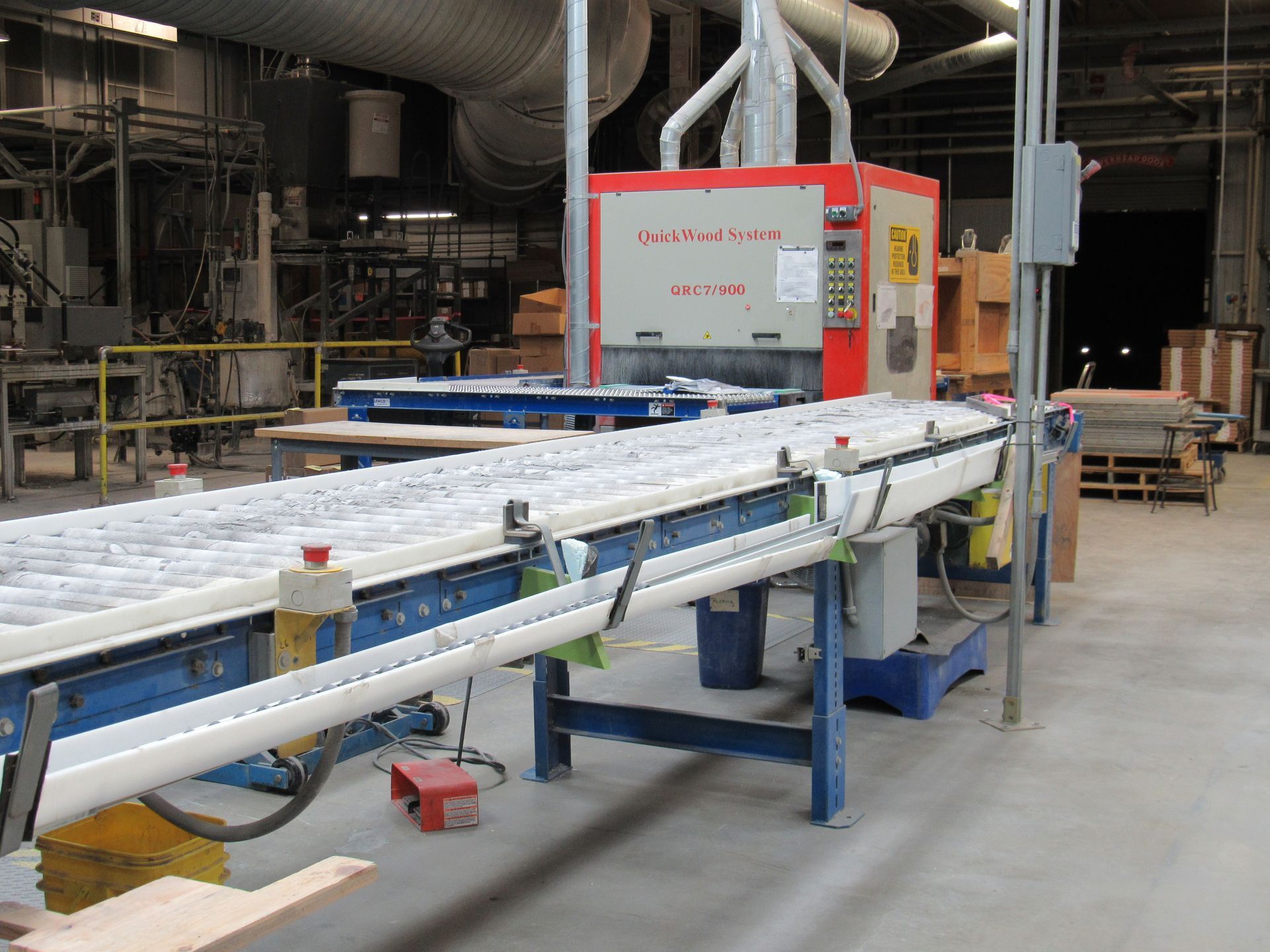Industrial sanding machine with a conveyor belt in a factory setting.