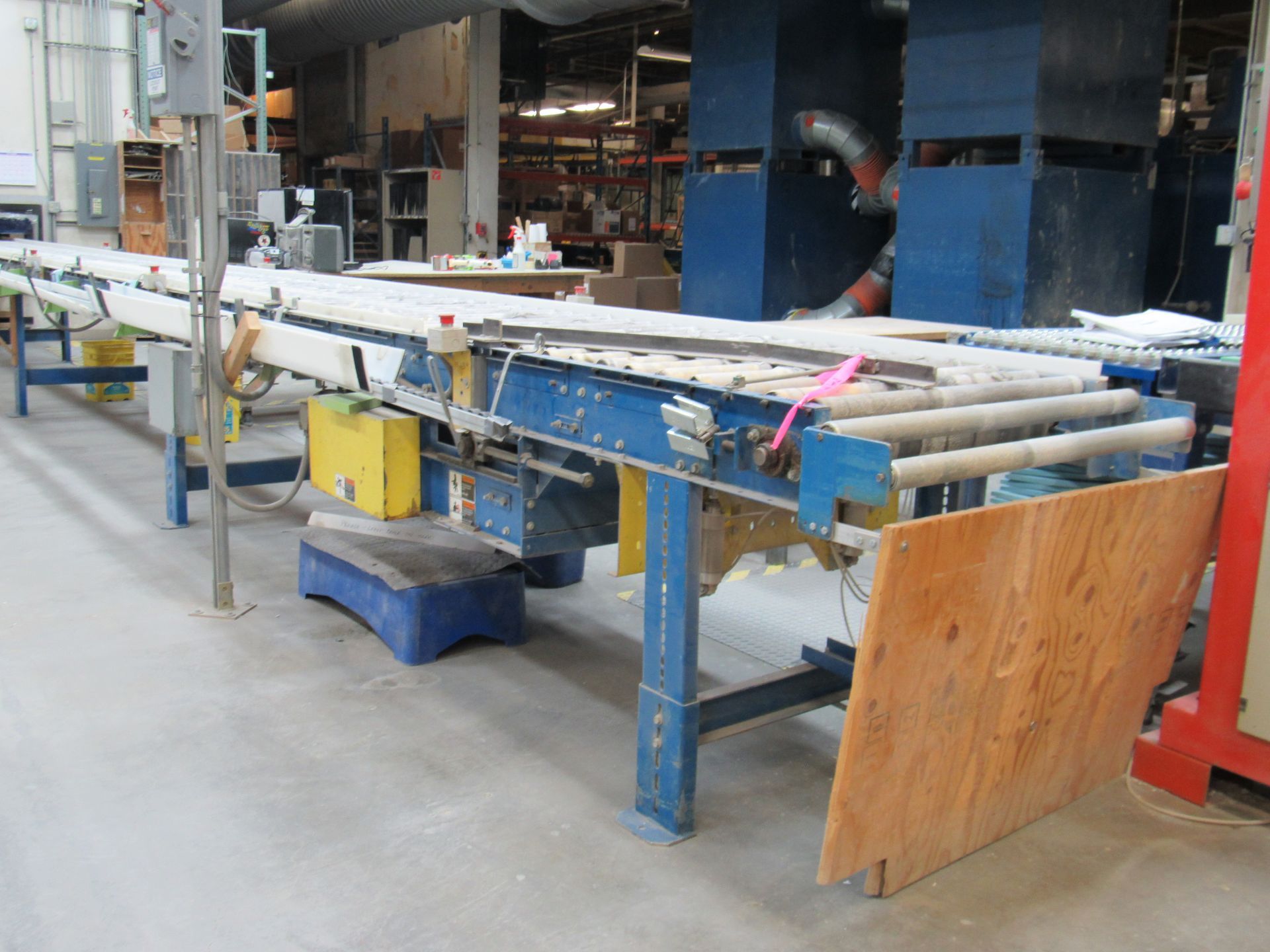 Long industrial conveyor belt with blue and metal supports in a warehouse setting.