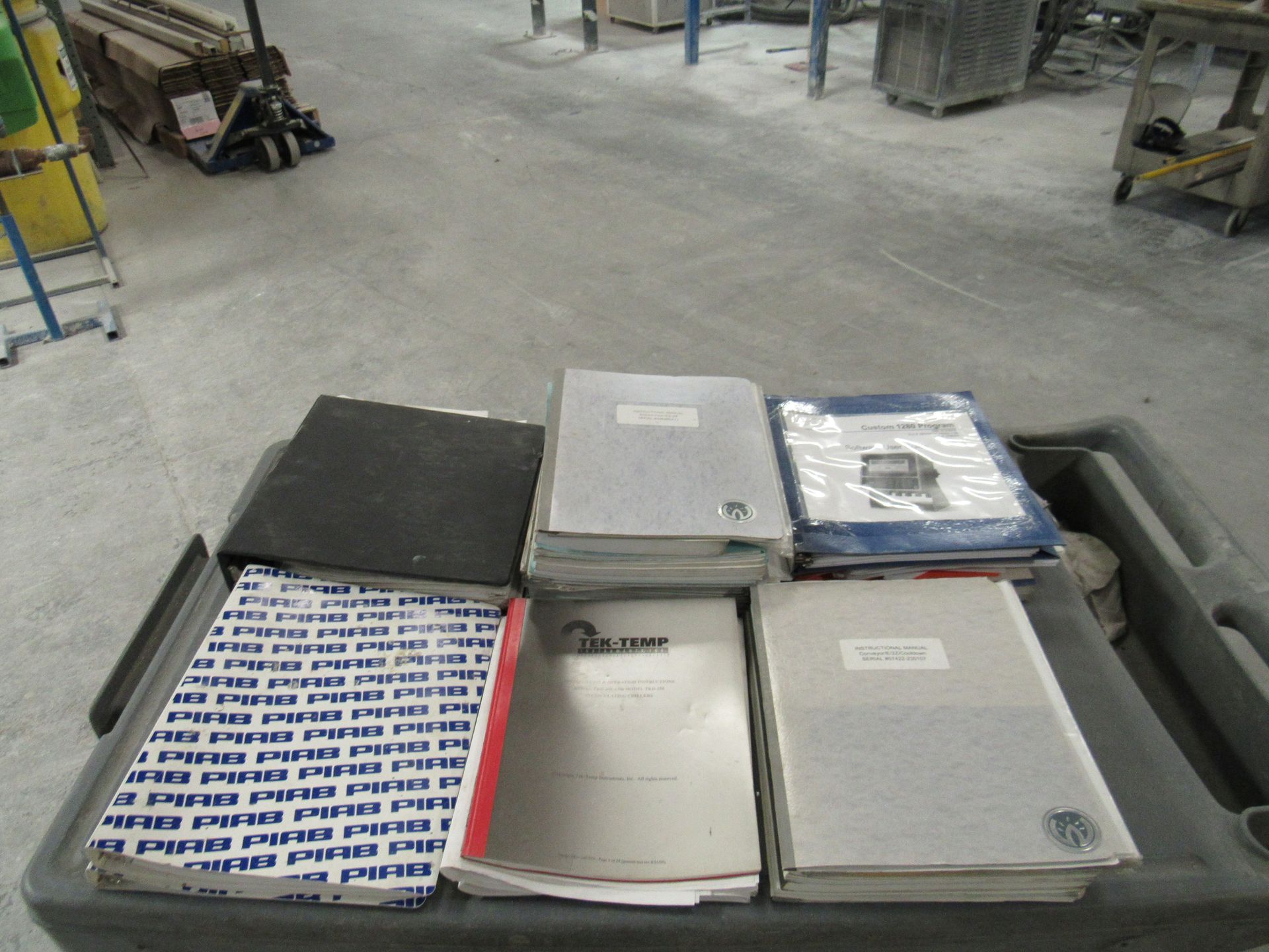 Books on a black container in an industrial setting, various colors and sizes.