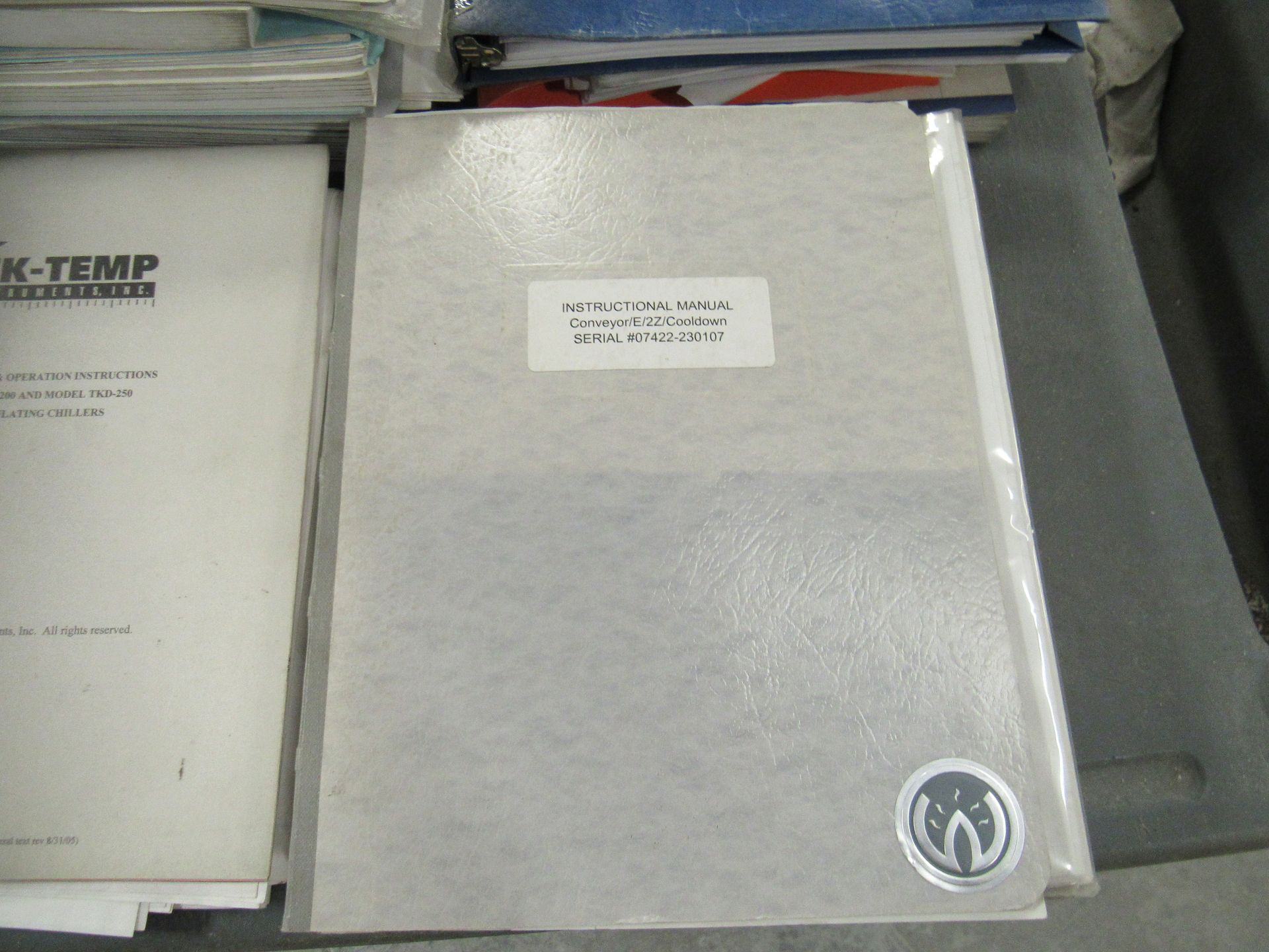 Gray binder with a white label, next to a white book; the scene is indoors, on a table.