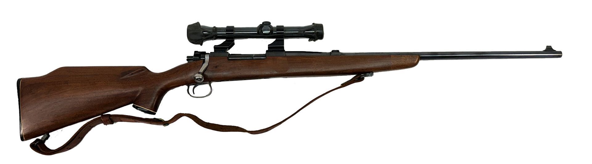 A brown bolt-action rifle with a scope, and a strap, against a white background.
