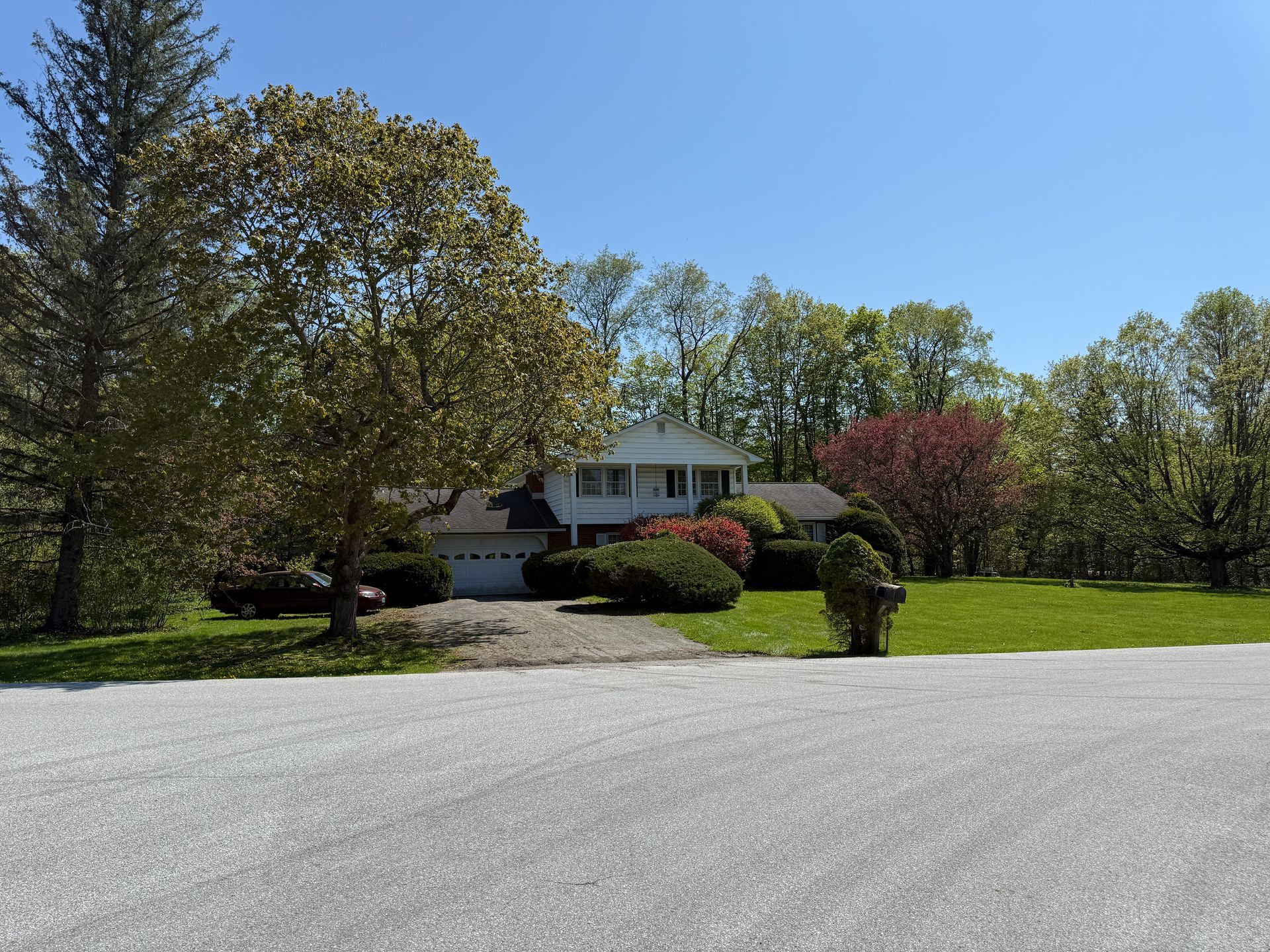 House with a white exterior, green lawn, trees, and blue sky.