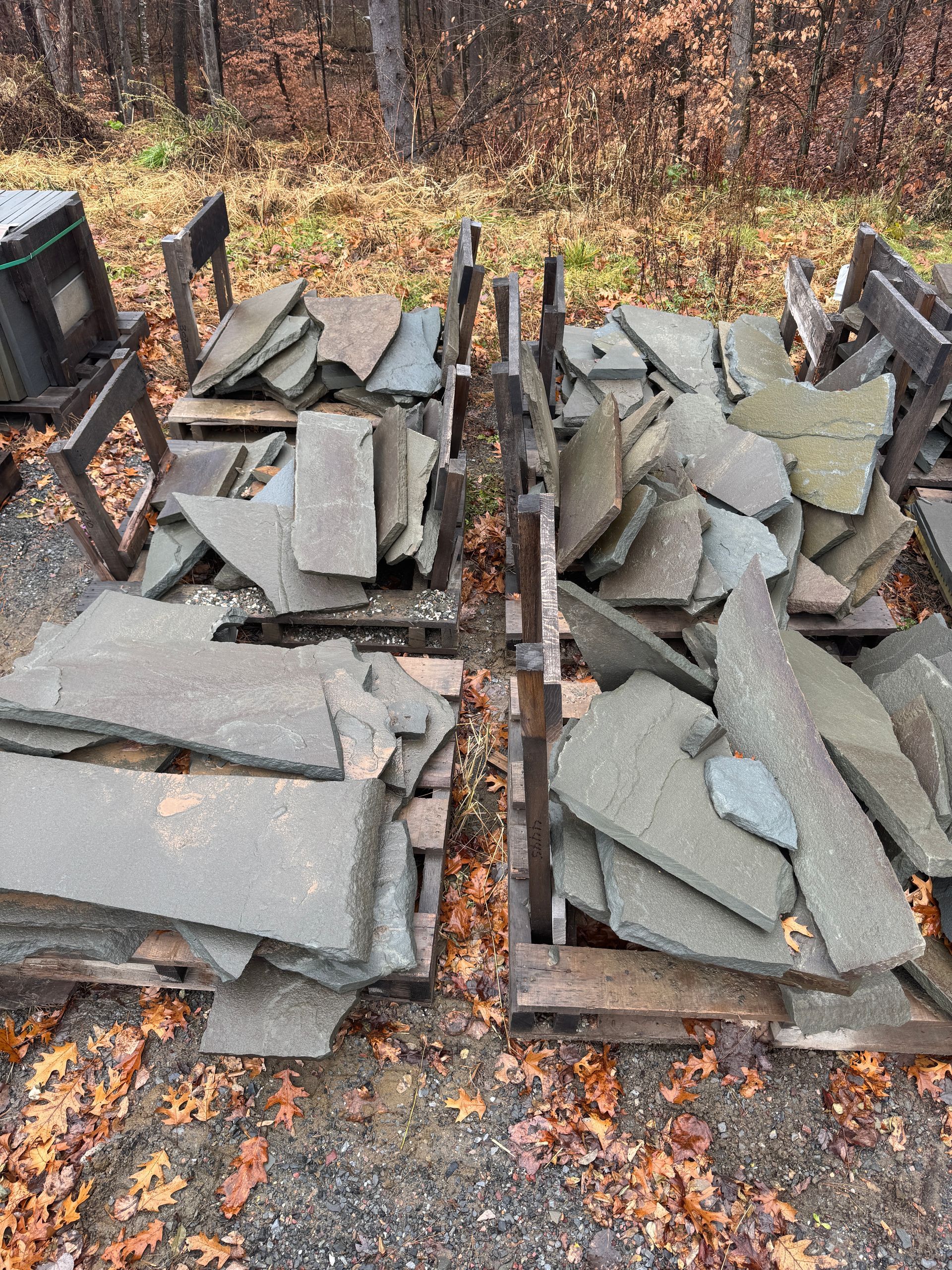 Pallets stacked with irregular gray stone slabs outside, ready for use.