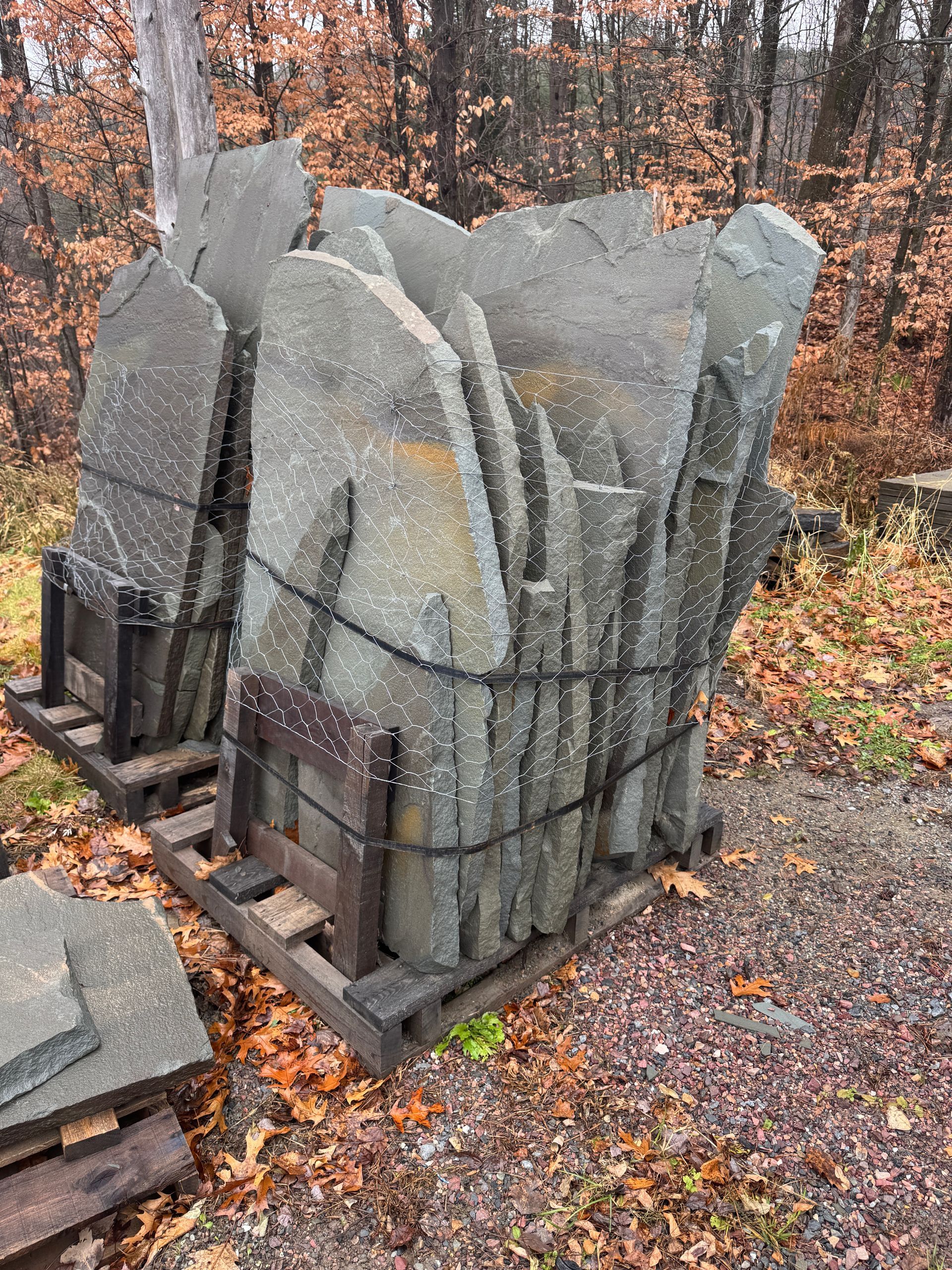 Stacked slate paving stones secured with straps on wooden pallets outdoors.