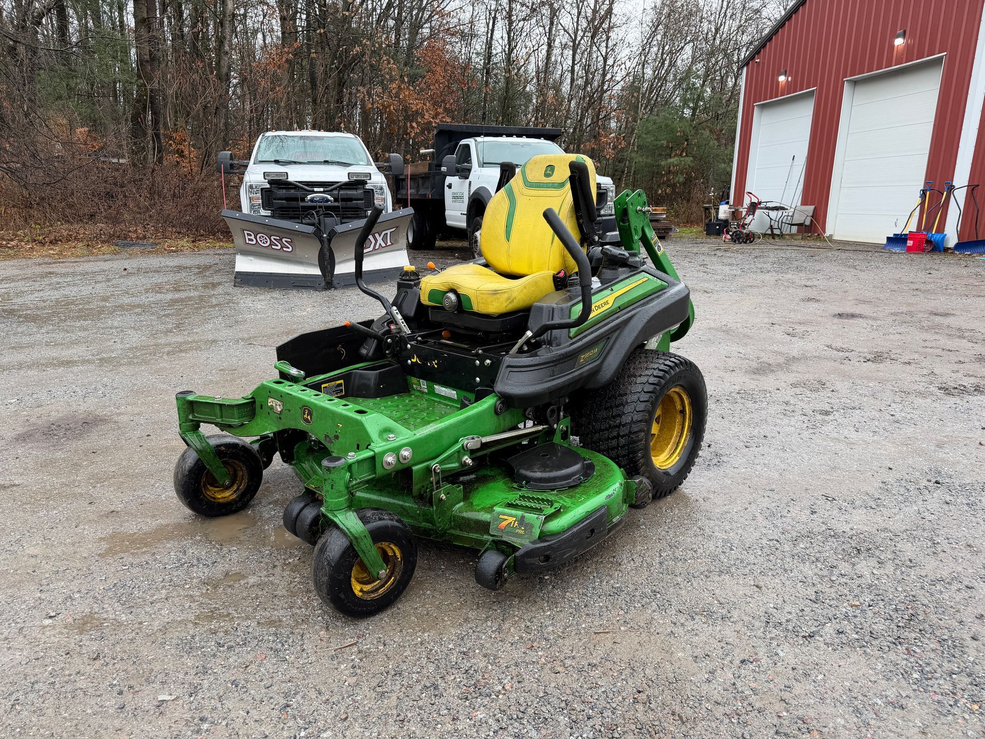 Green and yellow John Deere zero-turn lawnmower on gravel.