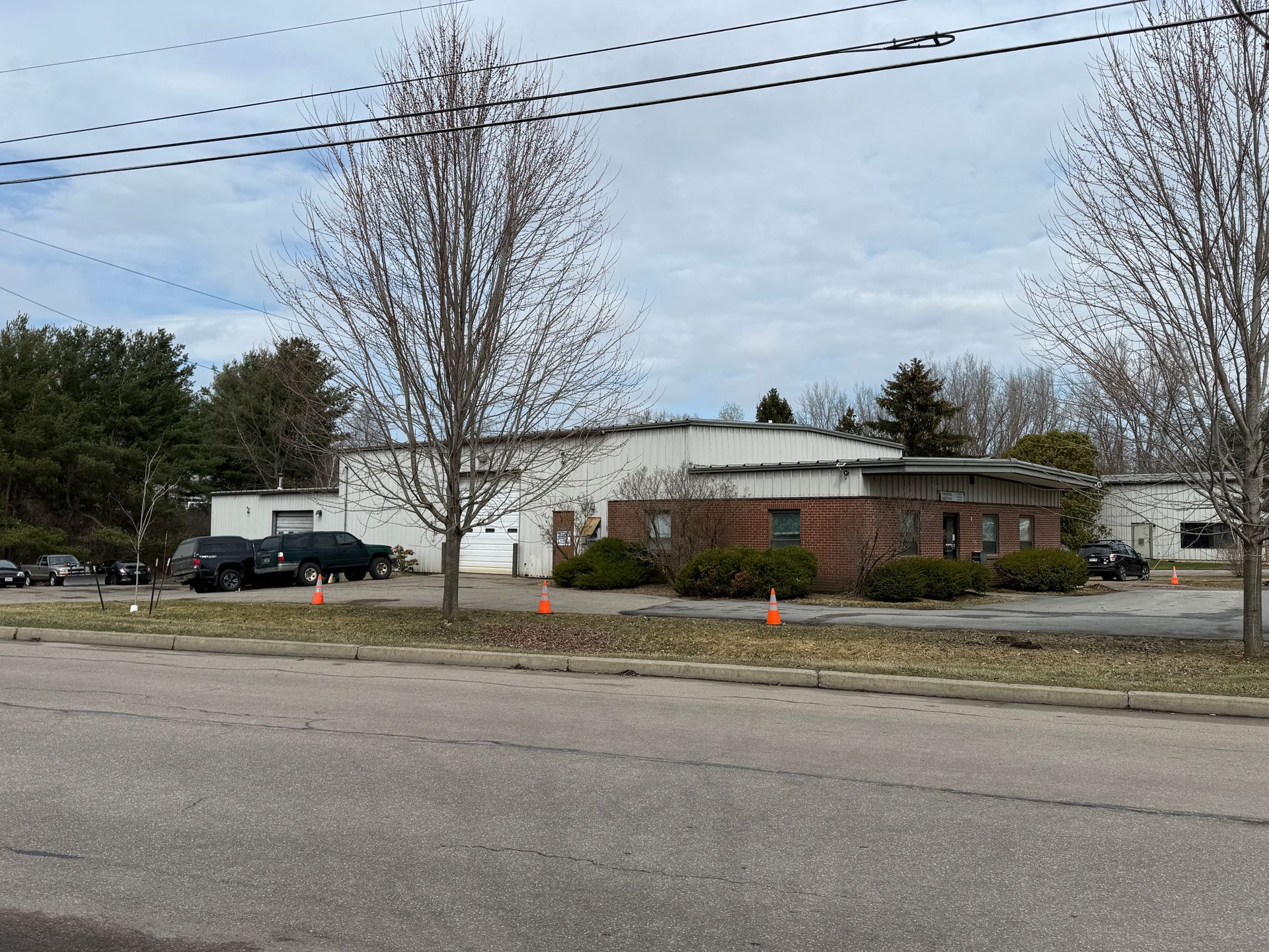 Suburban street view of a low white building with a brick front.