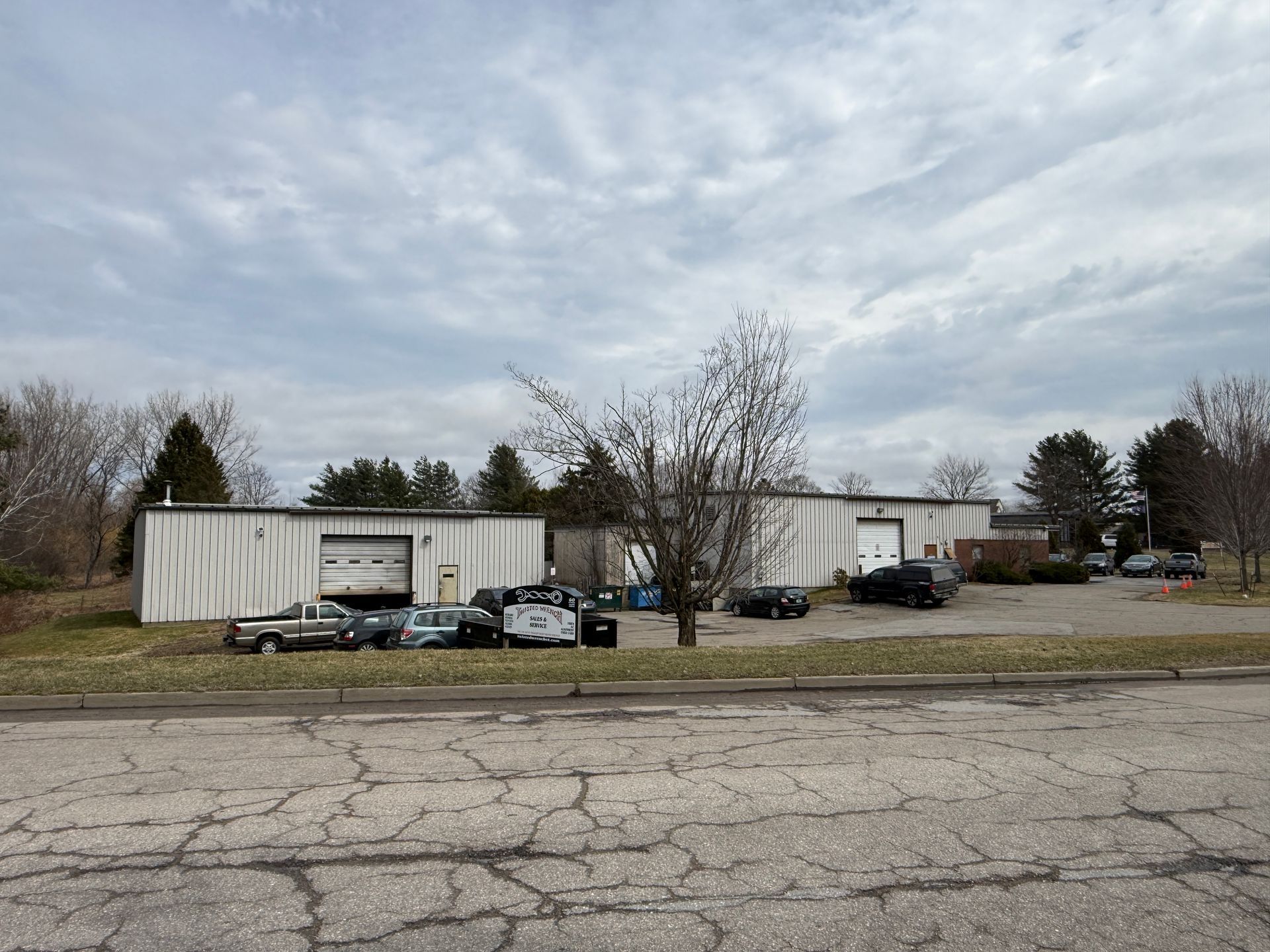 A row of parked cars beside white industrial buildings