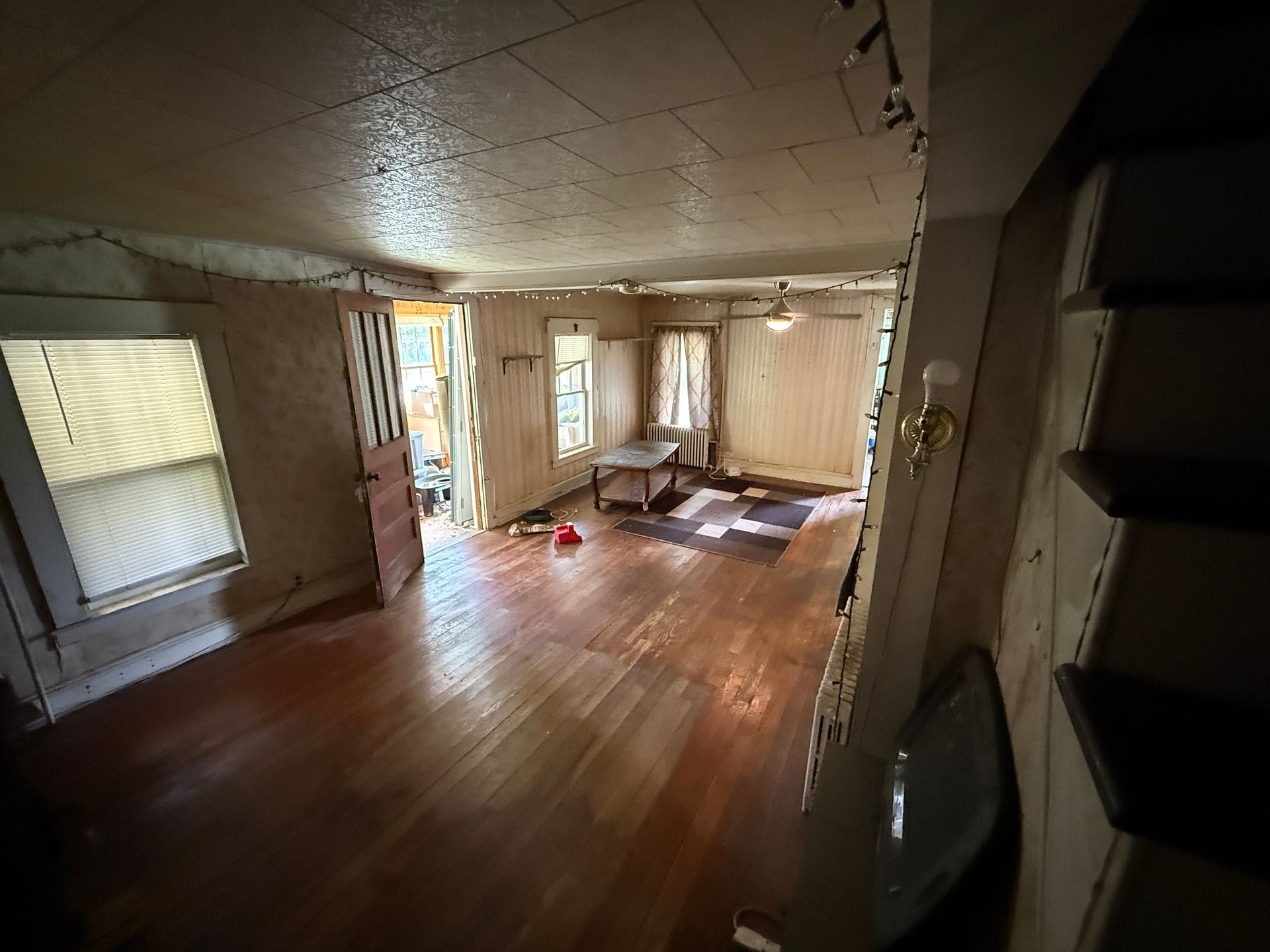 Empty living room with hardwood floors, ceiling, and sunlight through windows