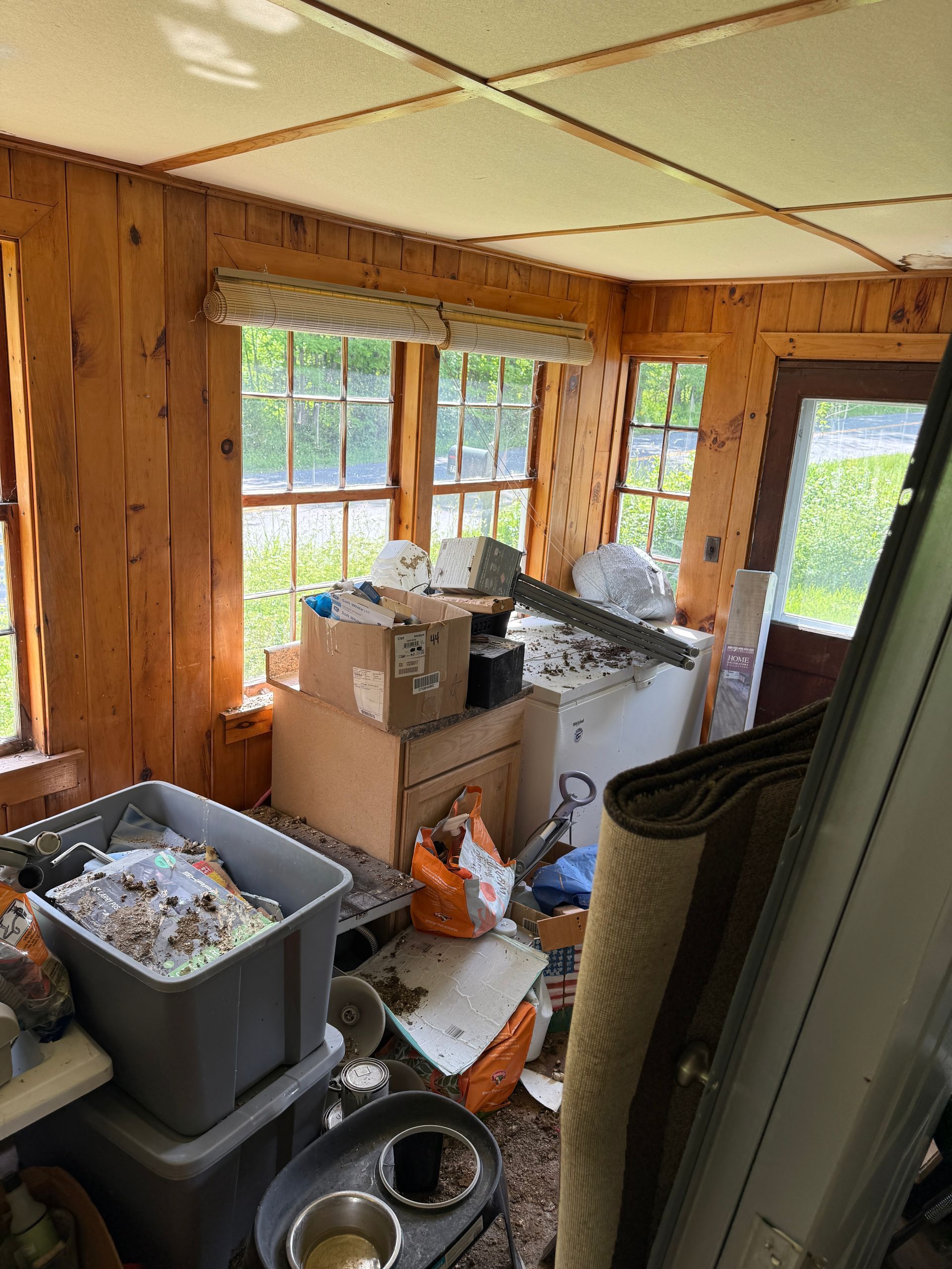 sunroom with boxes, bins beside large windows and a glass door