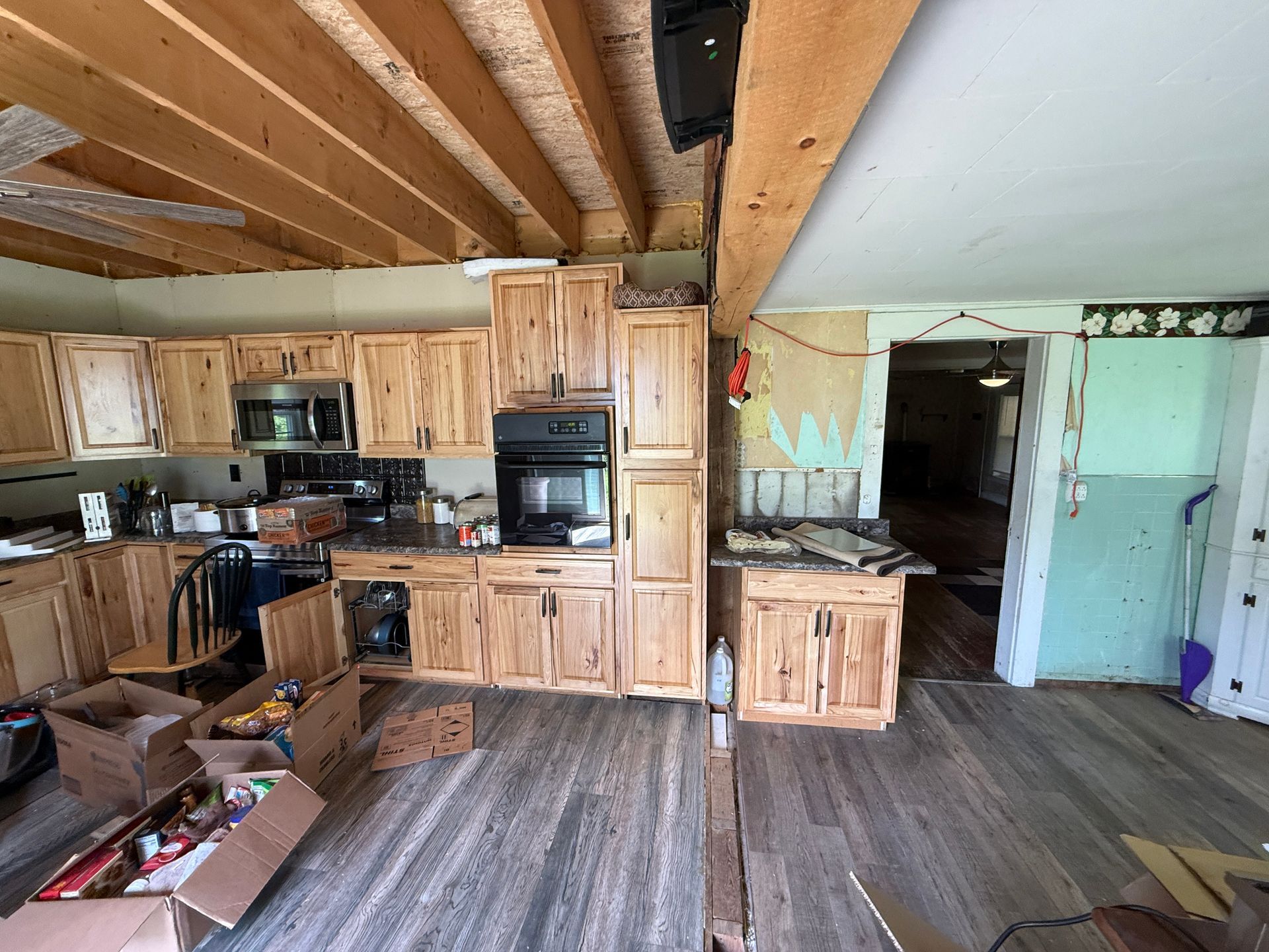 Rustic kitchen with wood cabinets, vaulted ceiling, and open doorway to a hallway