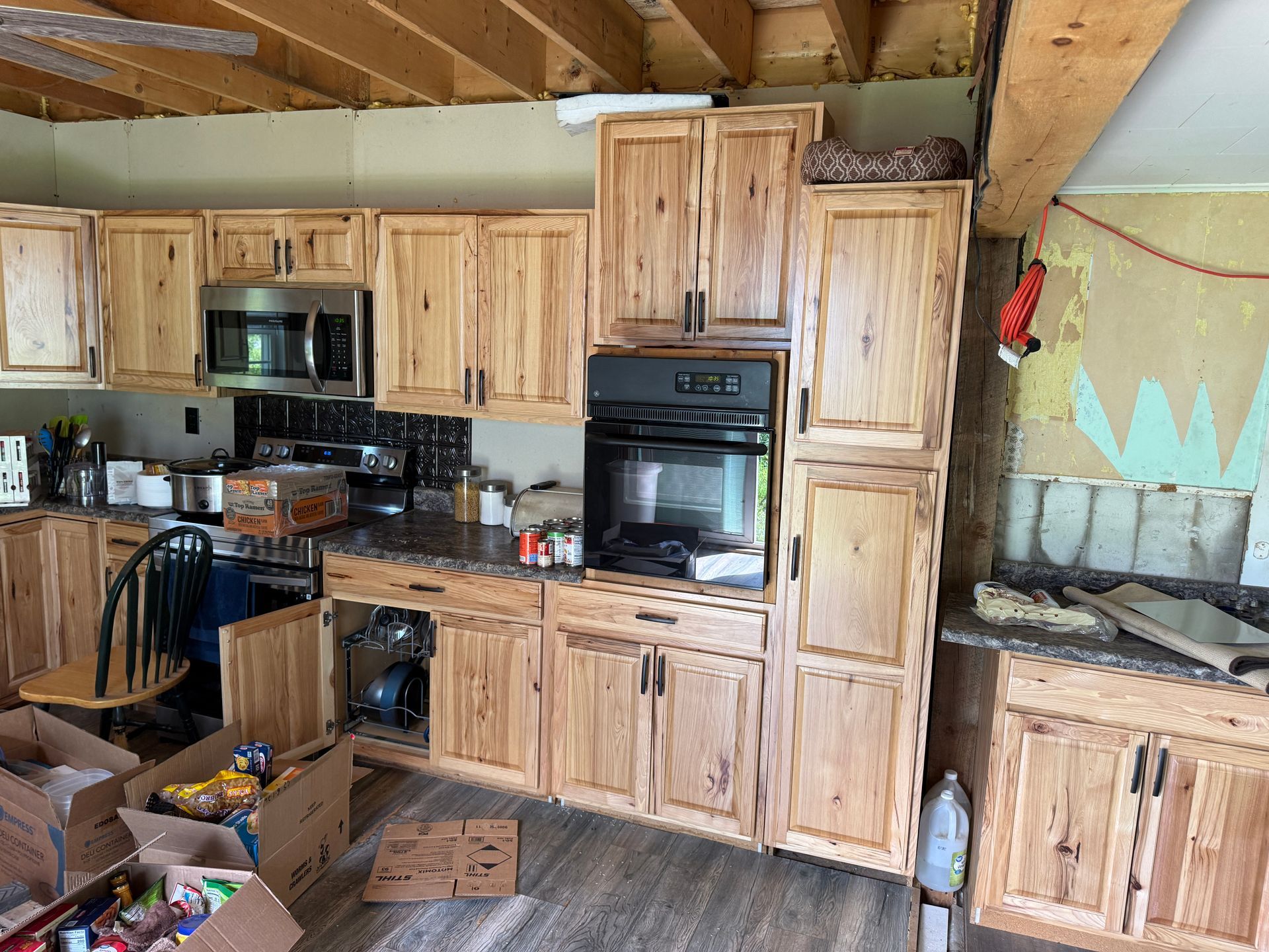 Rustic kitchen with wooden cabinets, built-in oven, microwave, and exposed beams