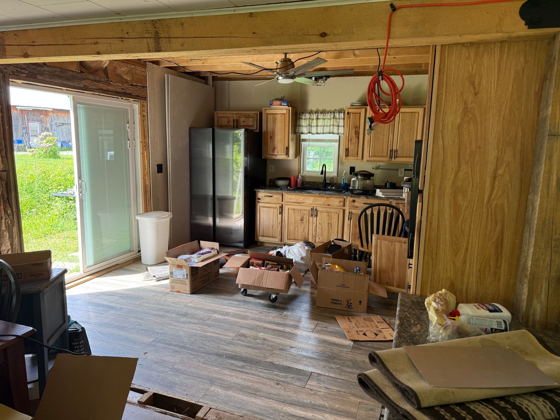 kitchen with boxes, cabinets, fridge, and an open door to the yard