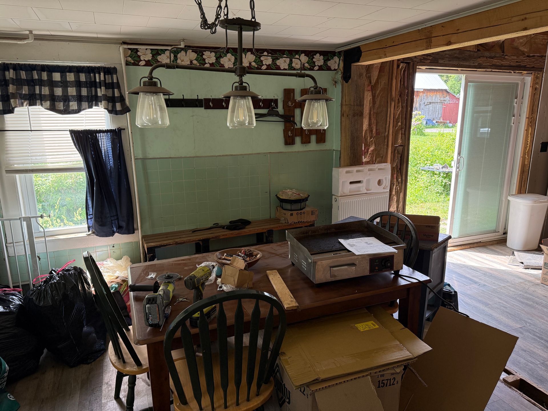 kitchen with a wooden table, hanging lights, and an open door to a bright patio