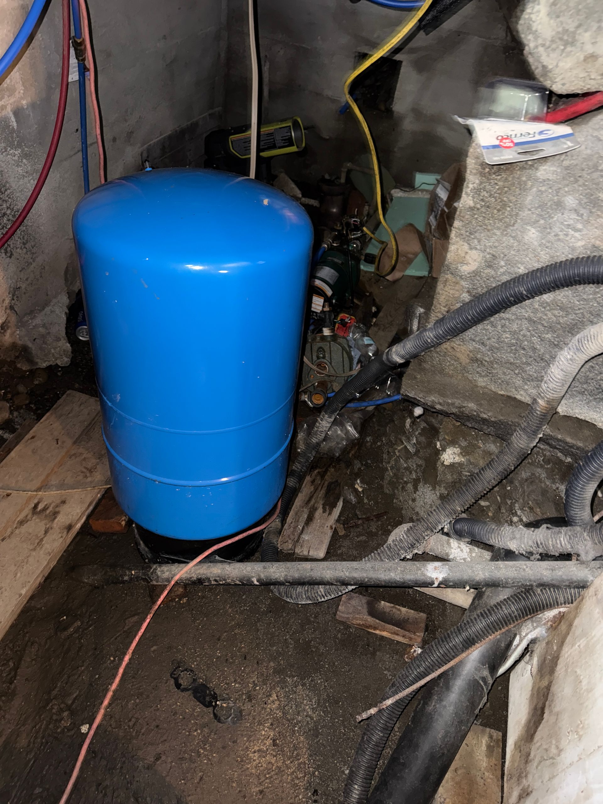 Blue pressure tank and exposed plumbing in a utility area