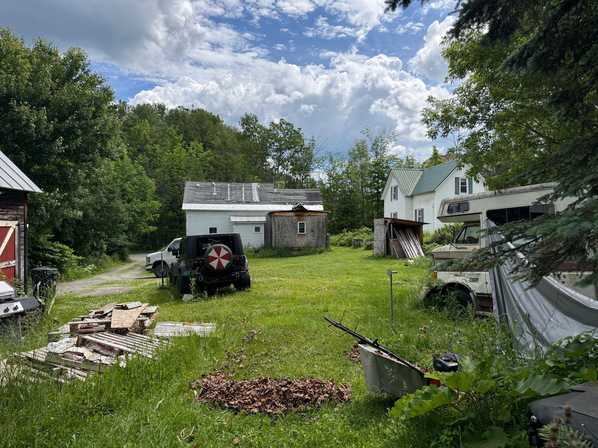 yard with a parked utility vehicle, and small sheds under a cloudy sky