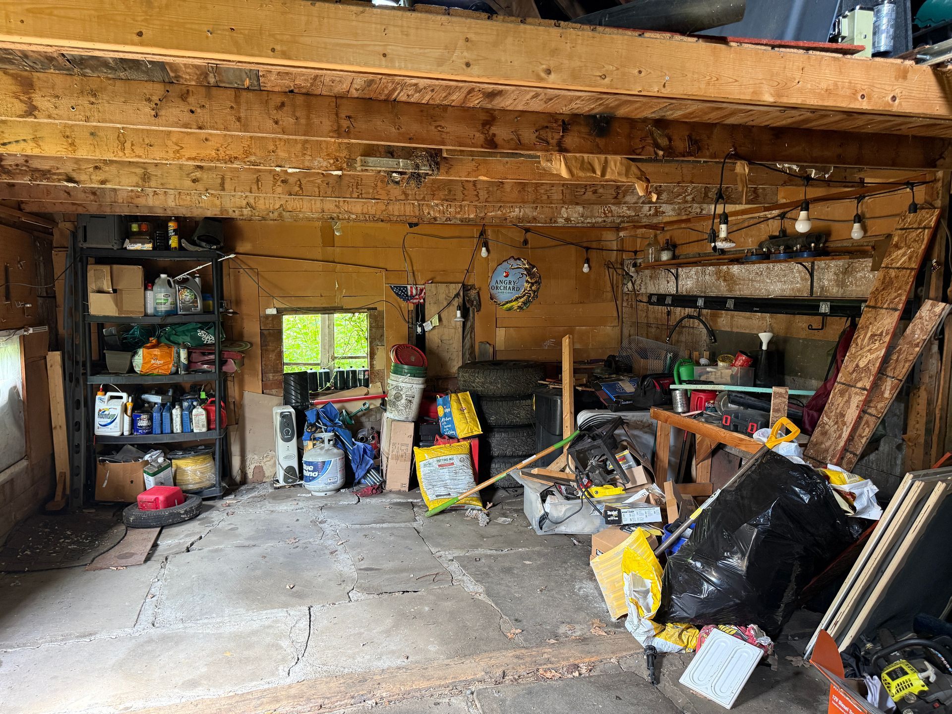 garage with tools, supplies under a low wooden ceiling.