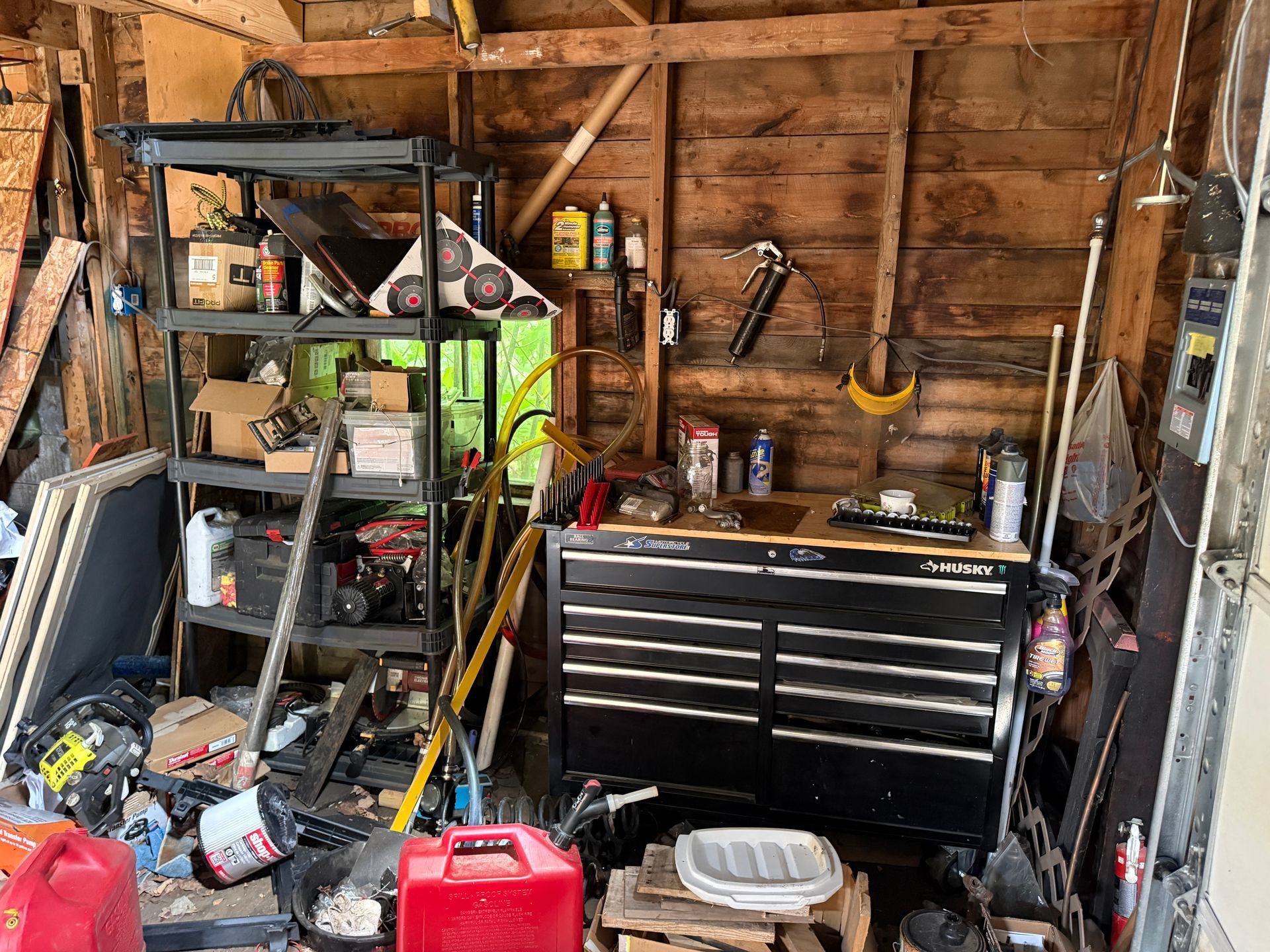 wooden shed with shelves, tools, a black tool chest