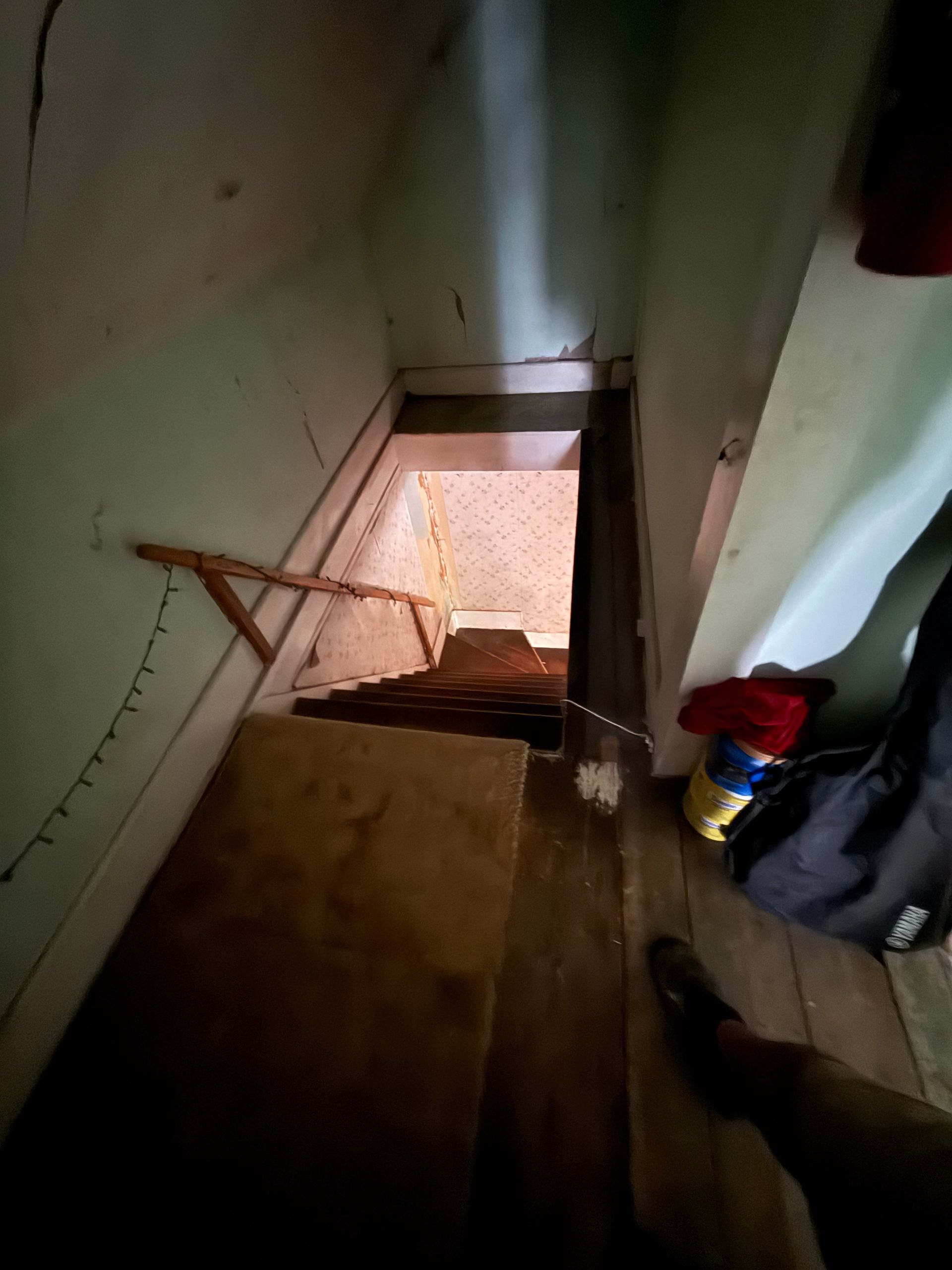 Narrow stairwell descending to a lower level, with a handrail