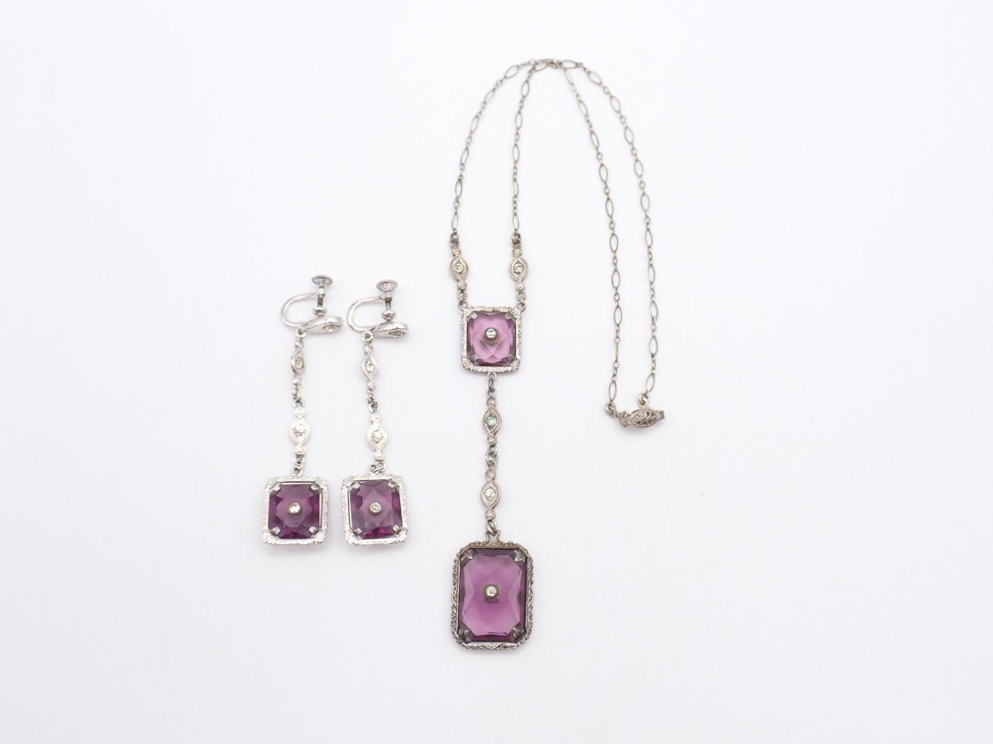 Purple gemstone necklace and matching earrings on a white background