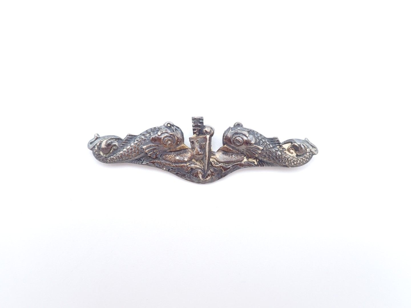 Small silver ornamental brooch with a central vertical detail on a white background