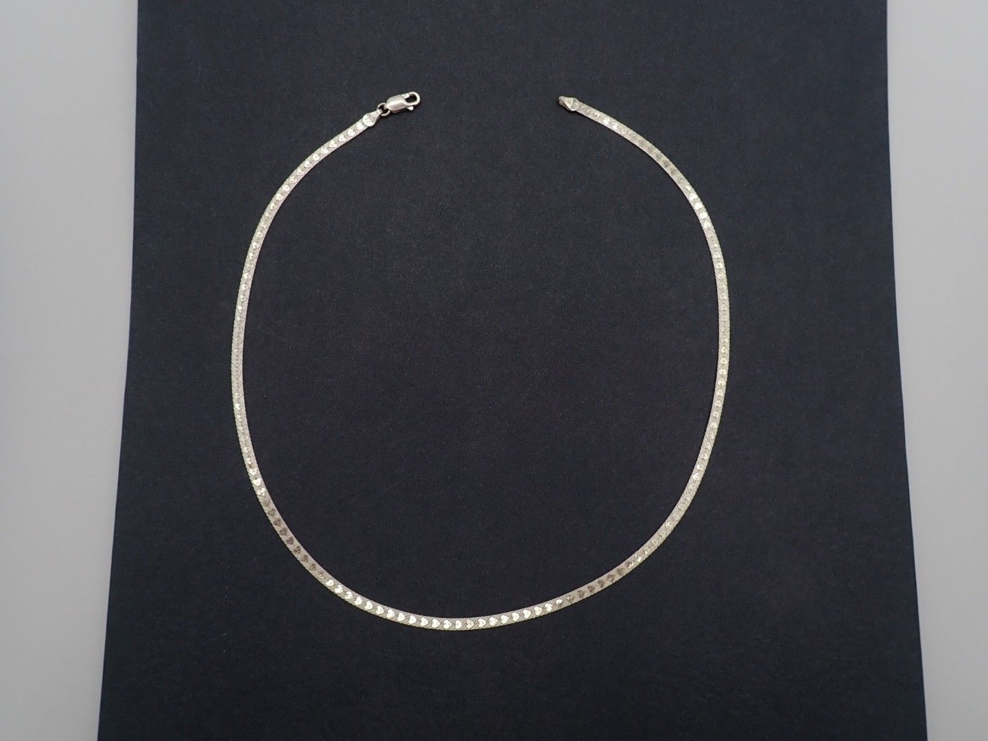 Silver necklace arranged in a circle on a black background