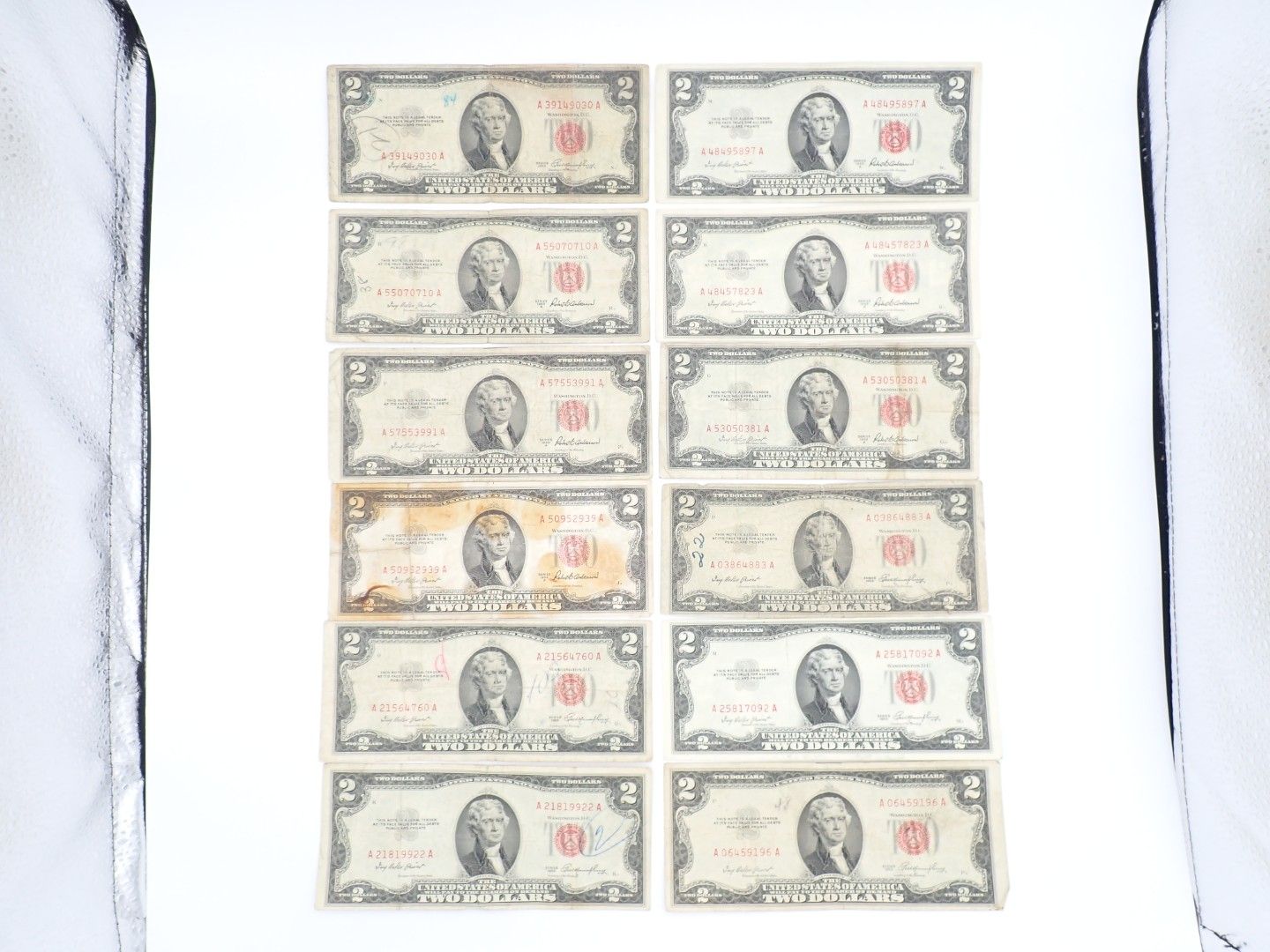 Two columns of old banknotes arranged in a grid on a white surface