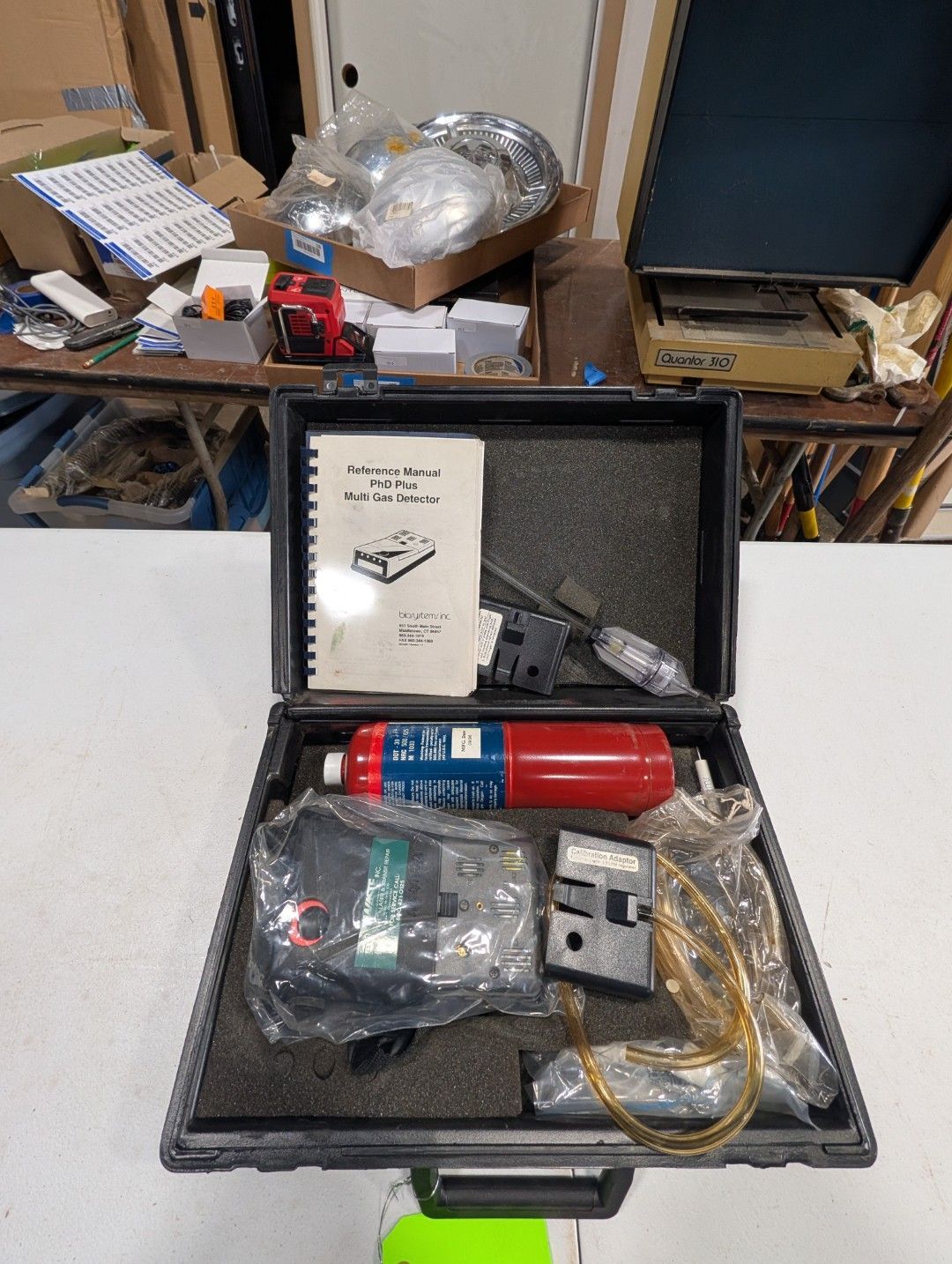 Open black toolbox with red canister, cords, and small parts