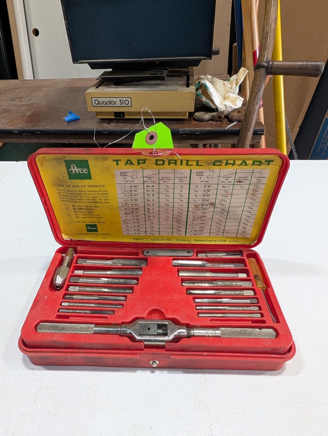 Open red tool case with metal bits, set on a table in a workshop.
