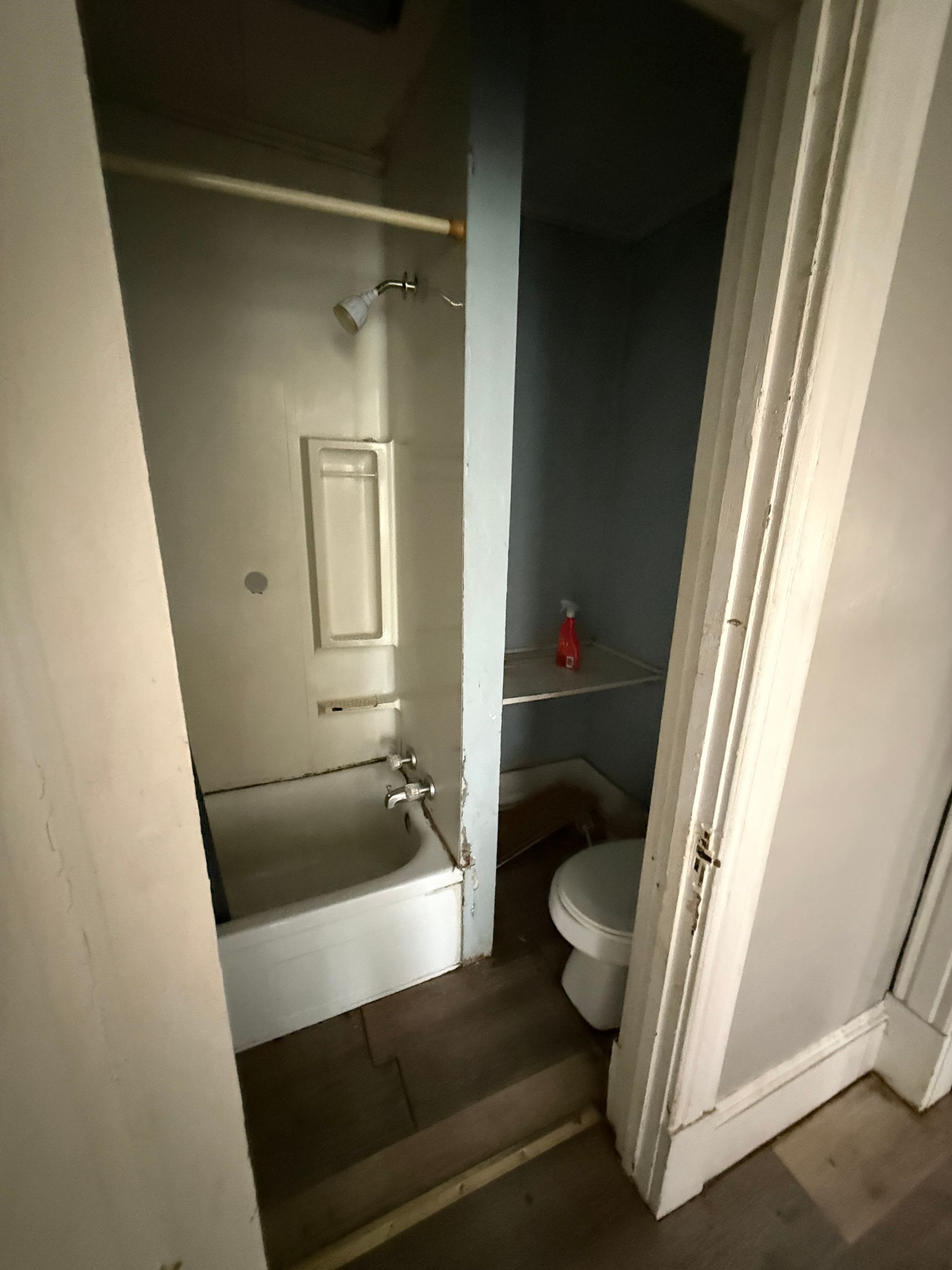 Small bathroom with a tub, sink, and toilet in a narrow hallway opening.