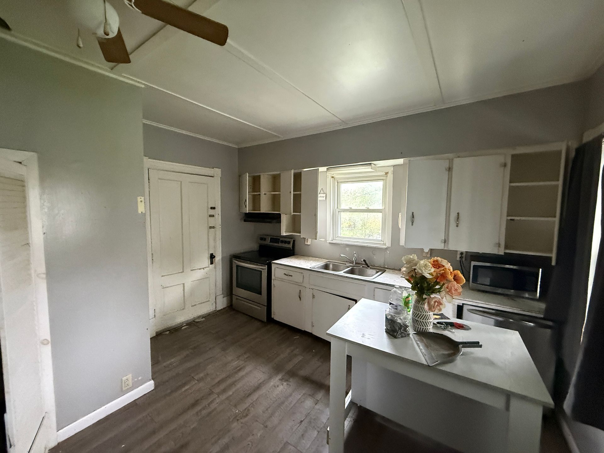 Bright kitchen with gray walls, white cabinets, stainless appliances, and an island with flowers.
