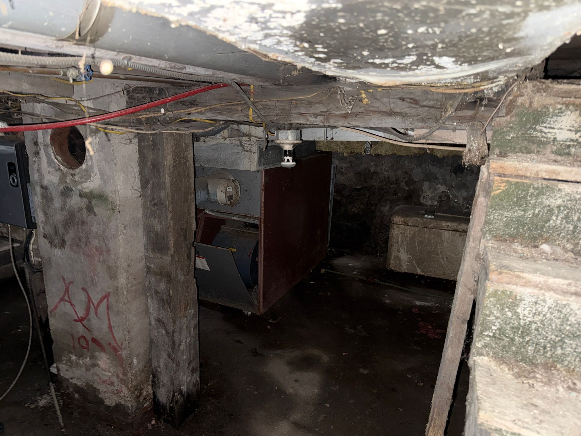 Crawlspace with concrete pillars and low overhead pipes
