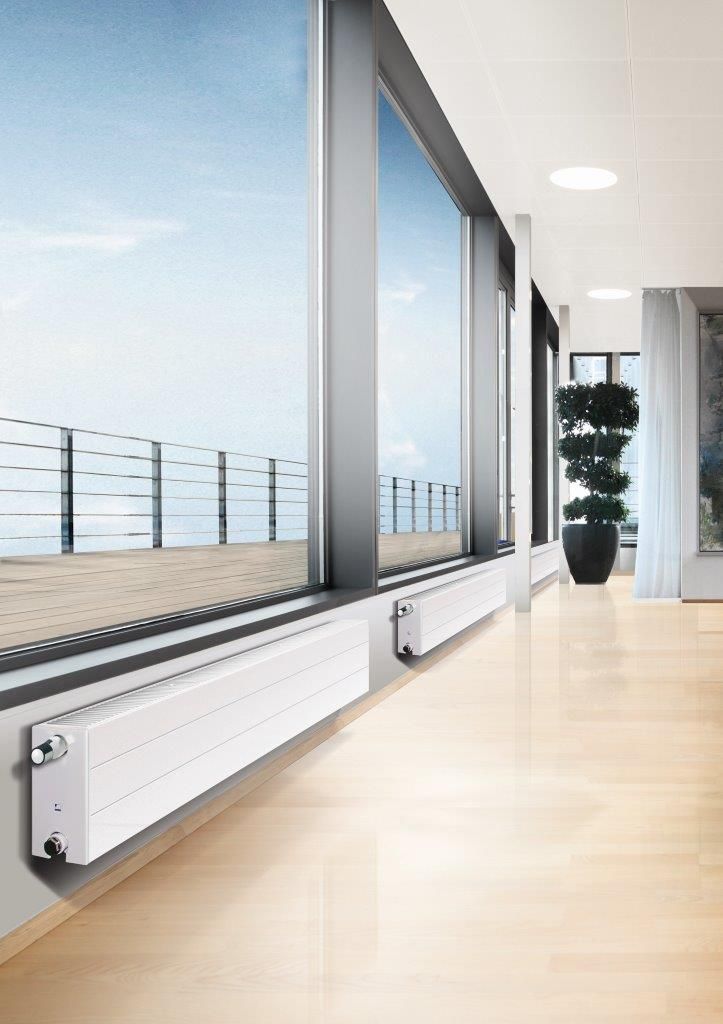 A modern room with large windows, a radiator, and a view of a deck and blue sky.