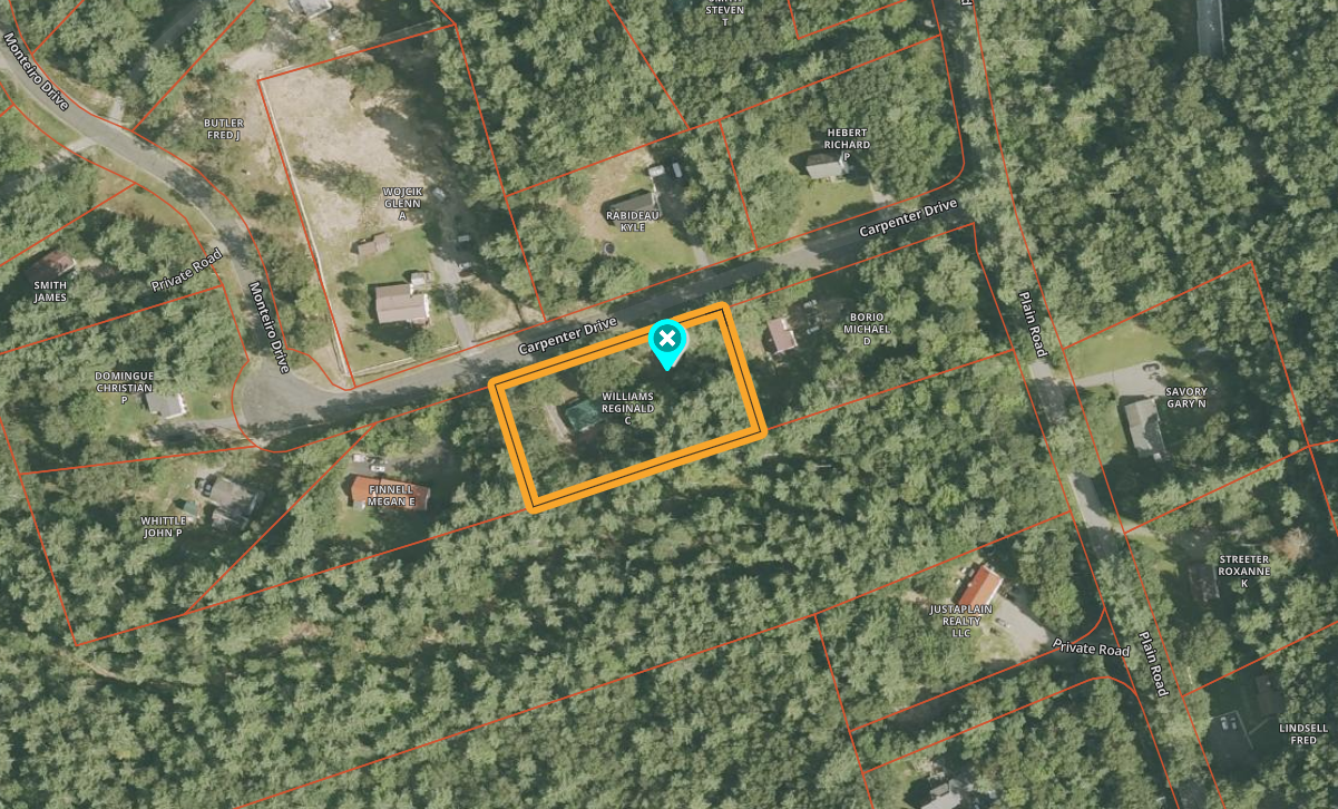 Aerial view of a wooded area with an orange-outlined plot marked by a blue location pin.