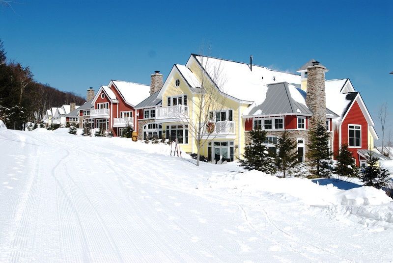 Row of colorful houses on a snow-covered hill. Winter scene with red, yellow homes. Sunny day.