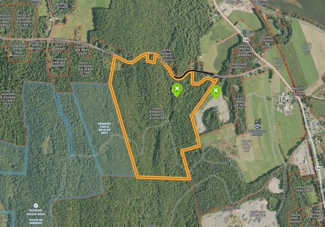 Satellite map showing an orange outlined property boundary with two green markers over forest and fields