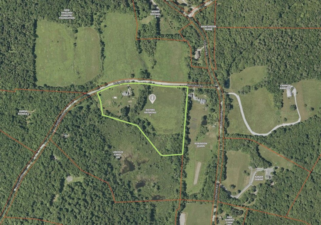 Aerial view of a rural property with a house and surrounding fields, outlined in green, and bordered by trees.