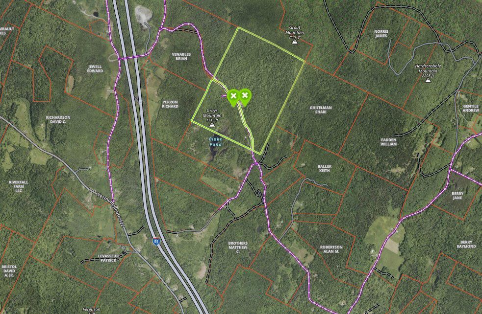 Aerial view of a forested area with a highlighted property outlined in green, alongside roads.